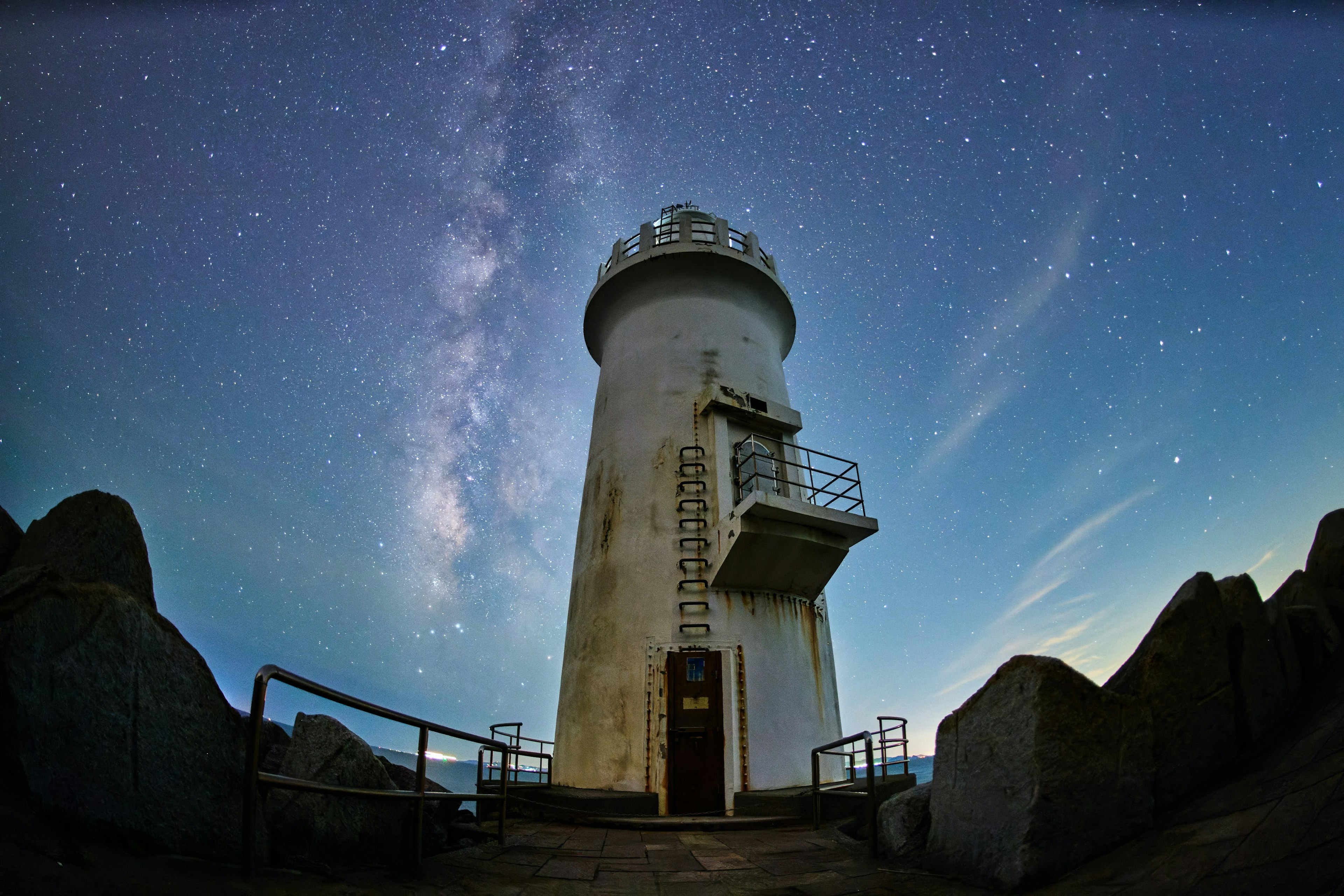 Ein Leuchtturm steht unter einem sternenklaren Himmel mit der Milchstraße sichtbar