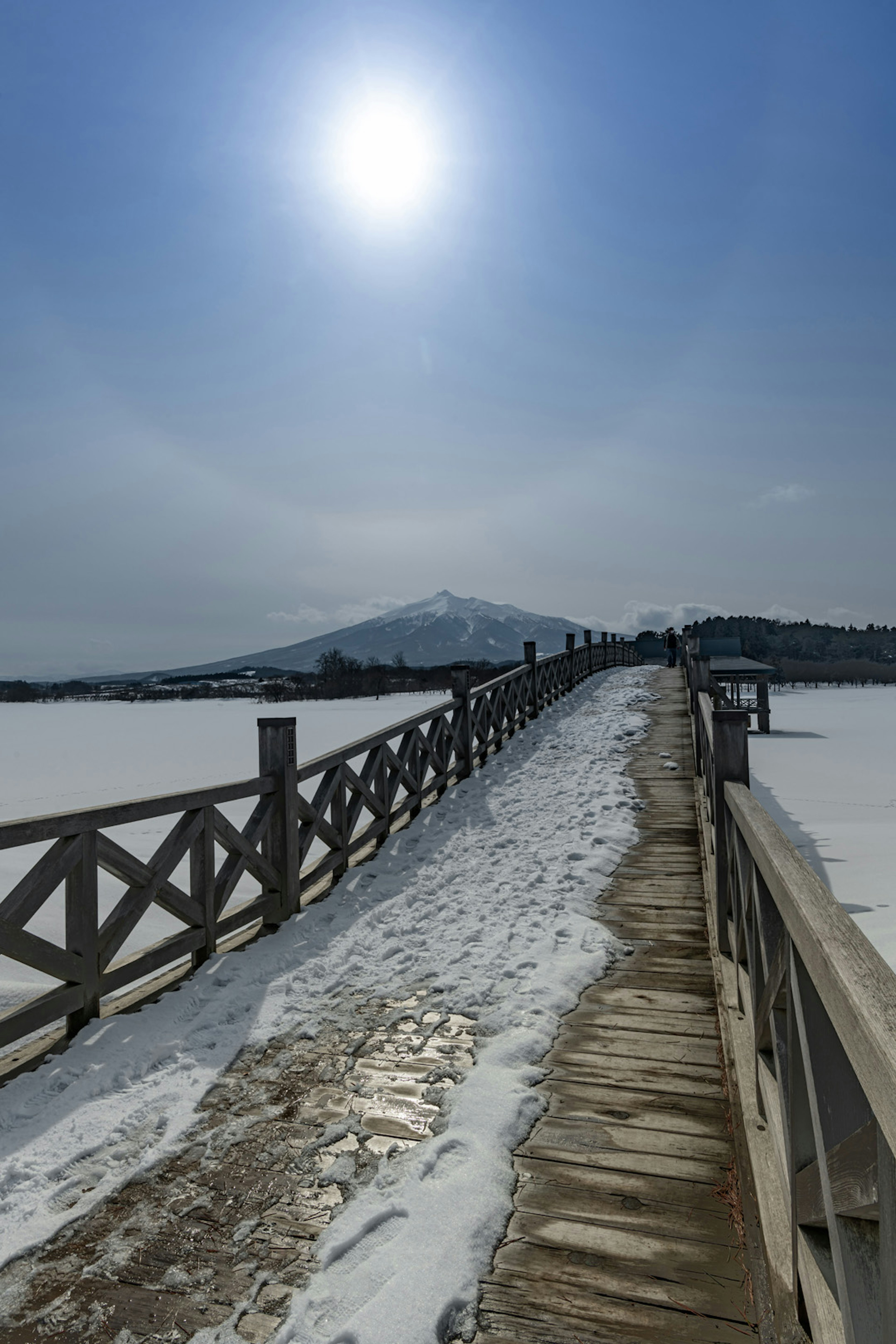 雪に覆われた桟橋と青空の下に輝く太陽