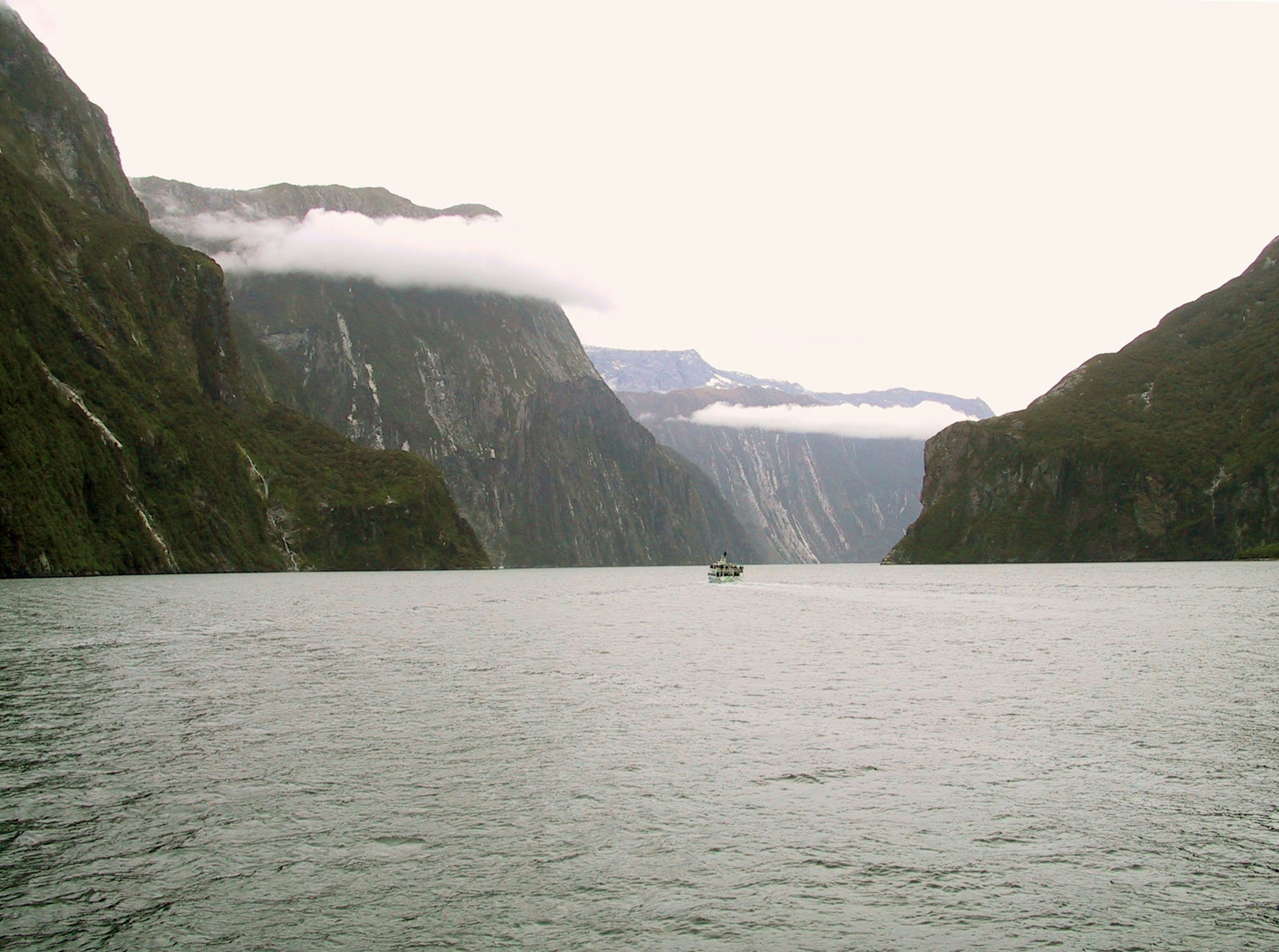 A small boat in a serene fjord surrounded by majestic mountains