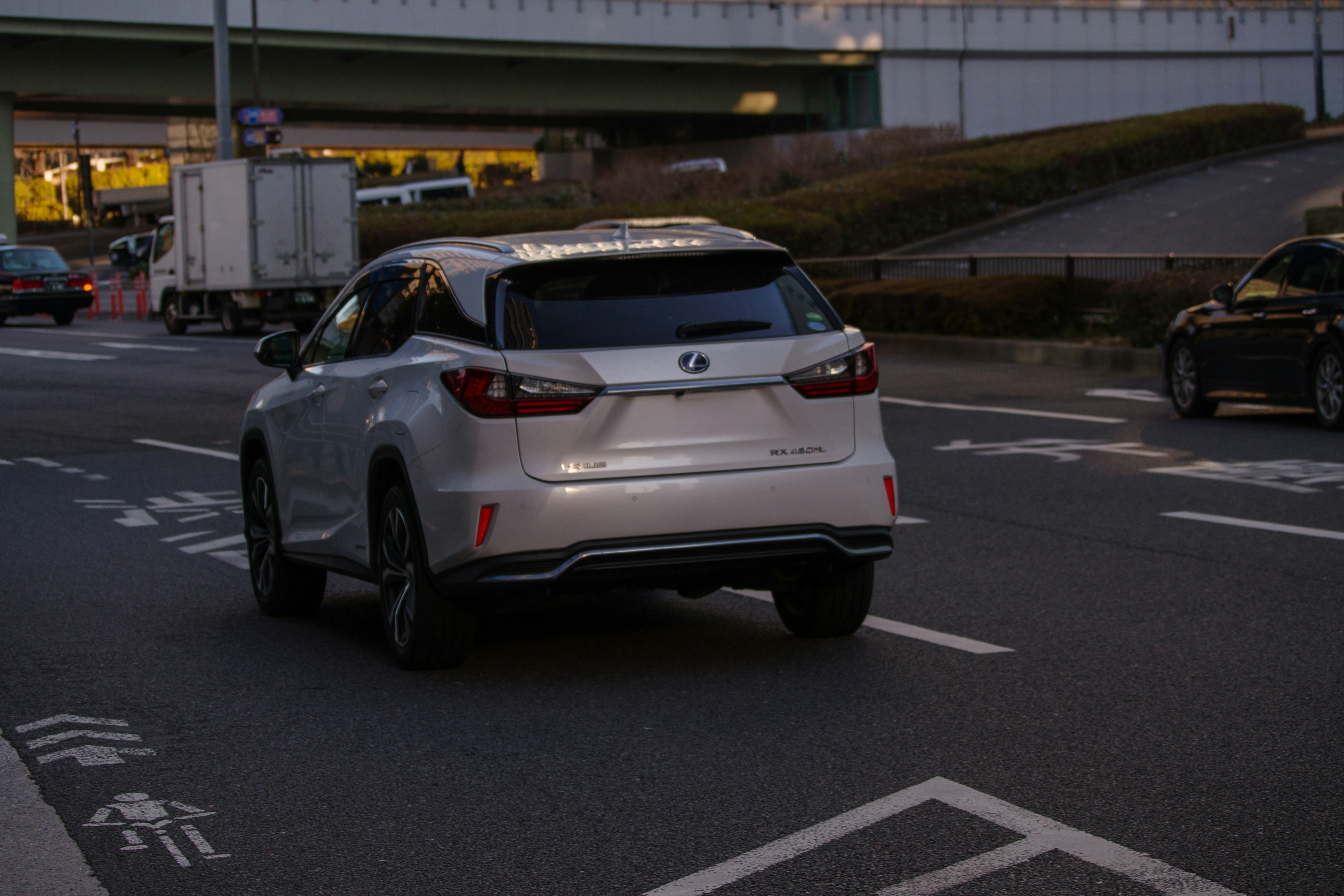 A white SUV driving on an urban road during dusk