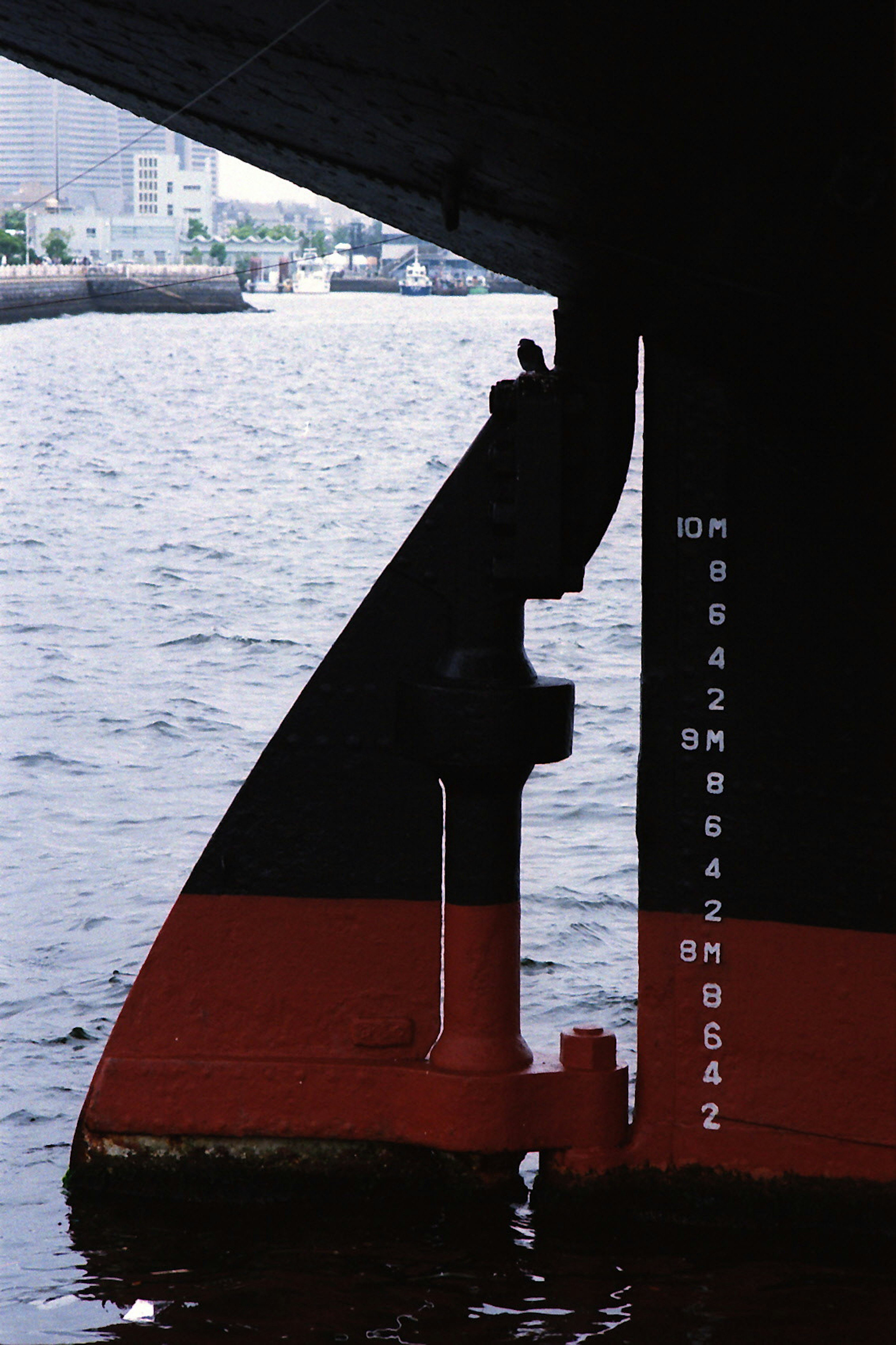 Bow of a ship with water reflection and urban background