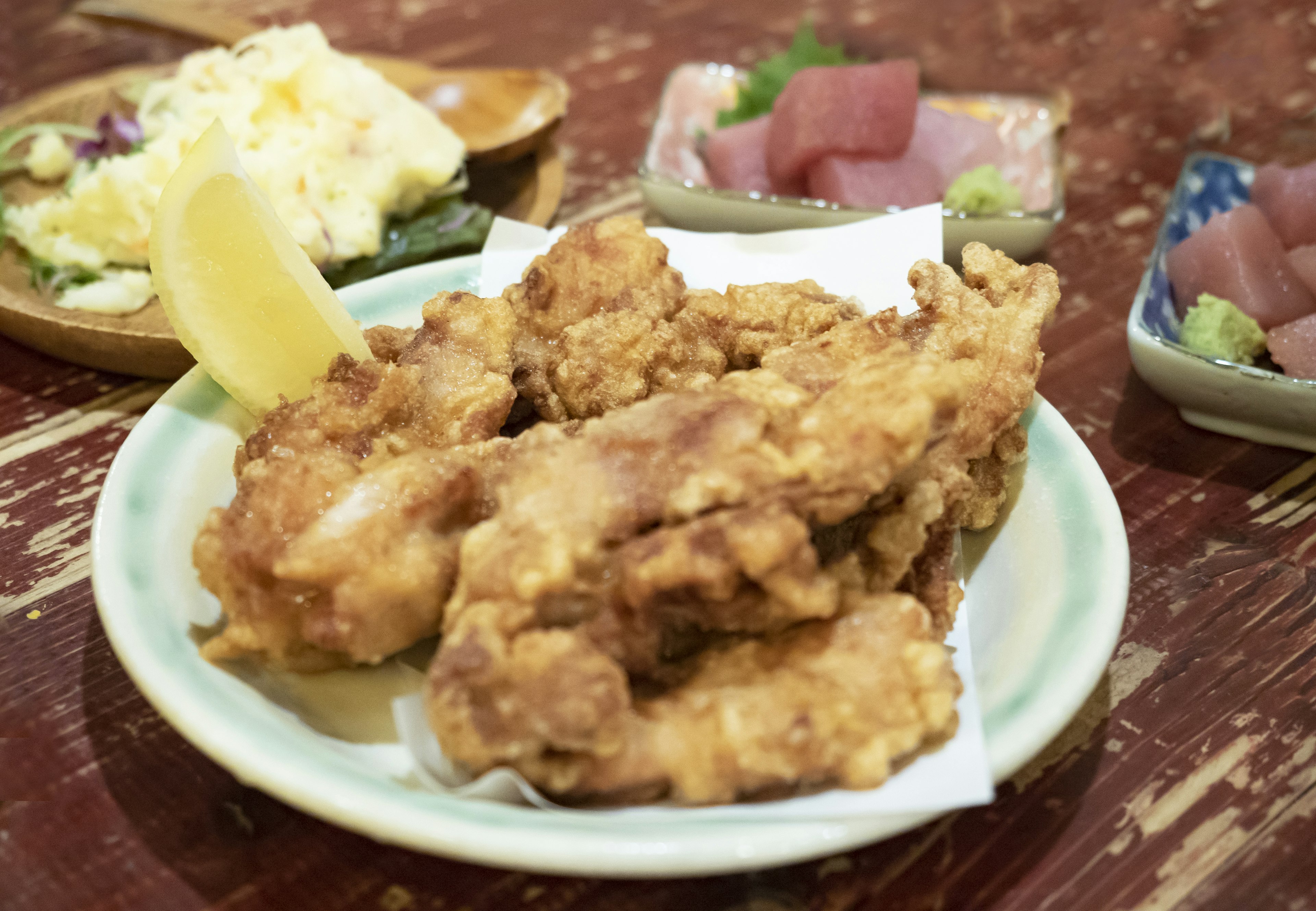 Plate of crispy fried chicken with sides of sashimi and salad