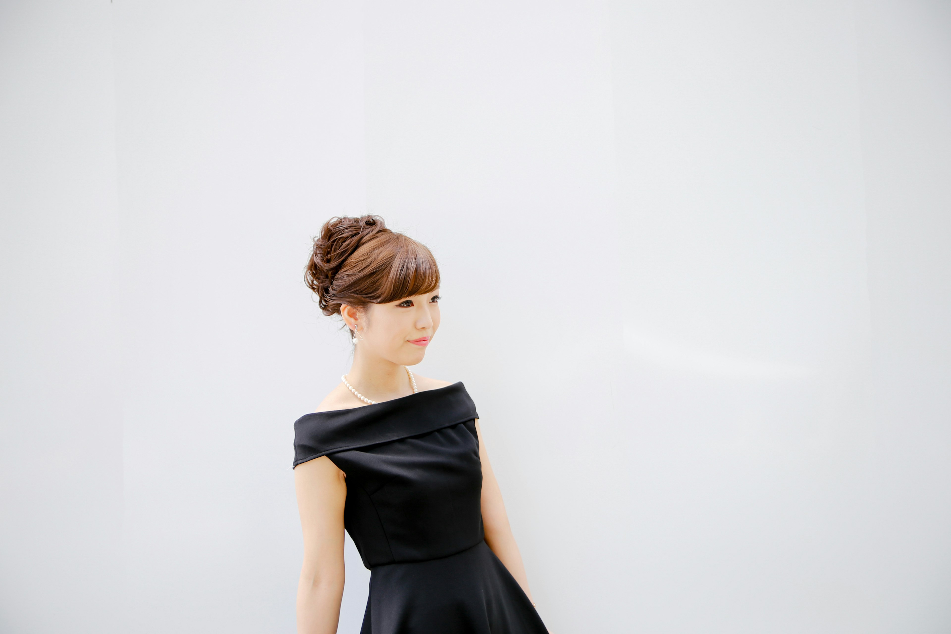 Une femme en robe noire se tenant devant un mur blanc