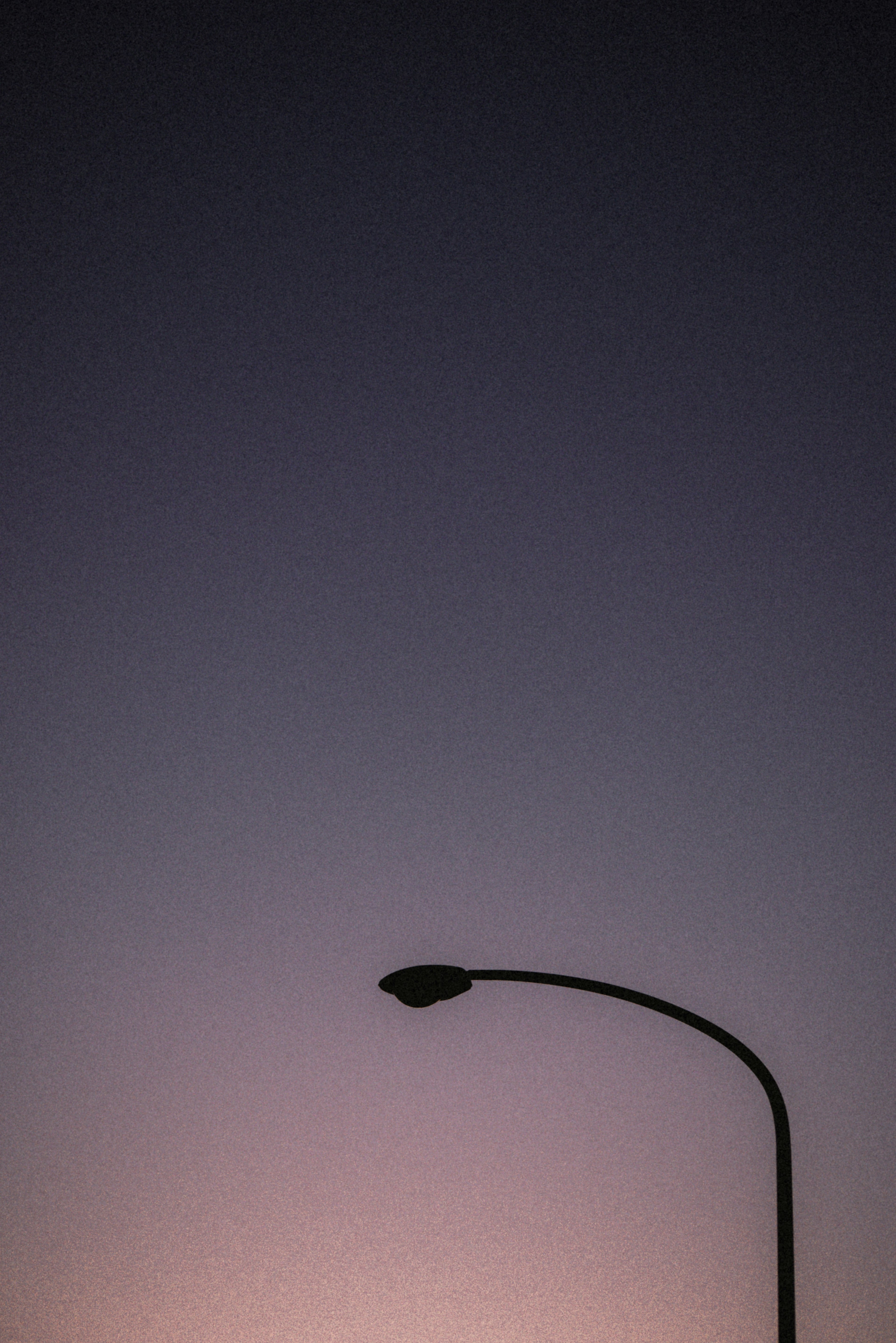 Silhouette of a streetlight against a dusky sky