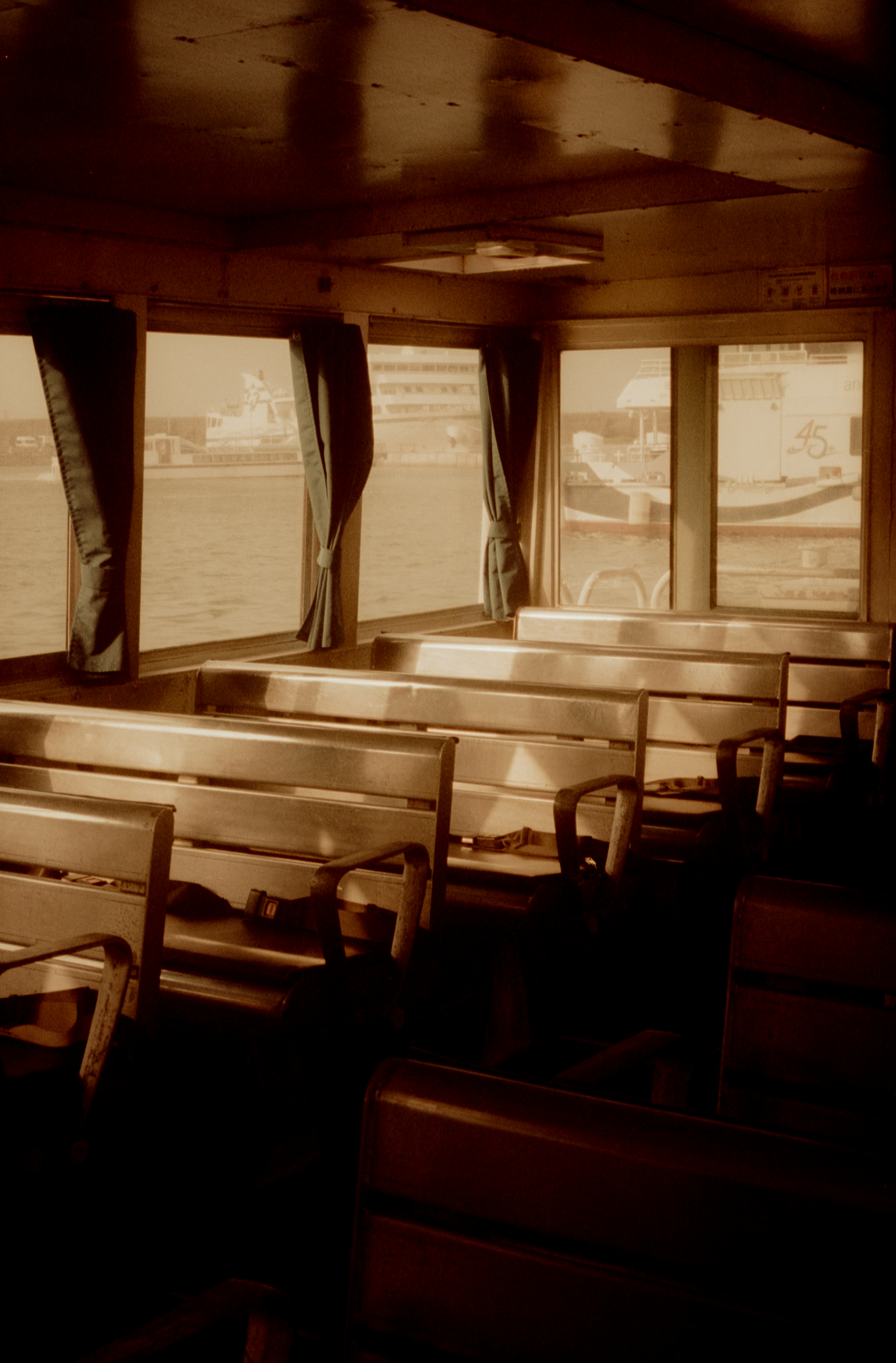 Interior of a boat featuring wooden benches and large windows