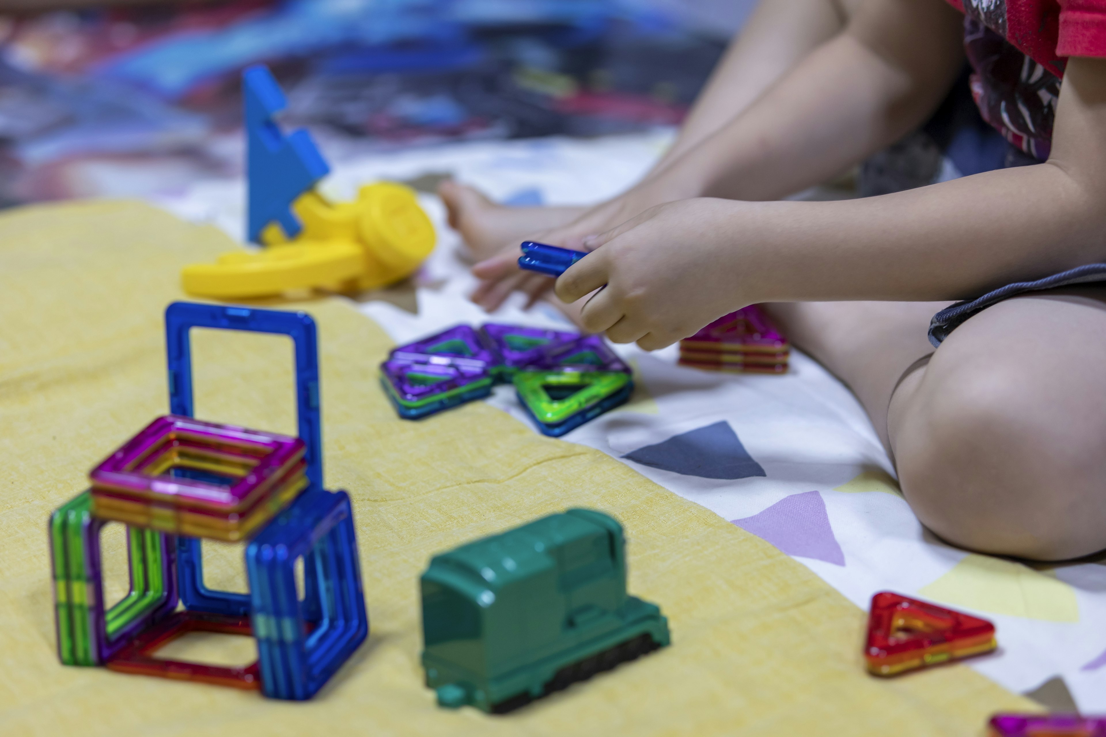 Child playing with colorful building blocks on a yellow mat