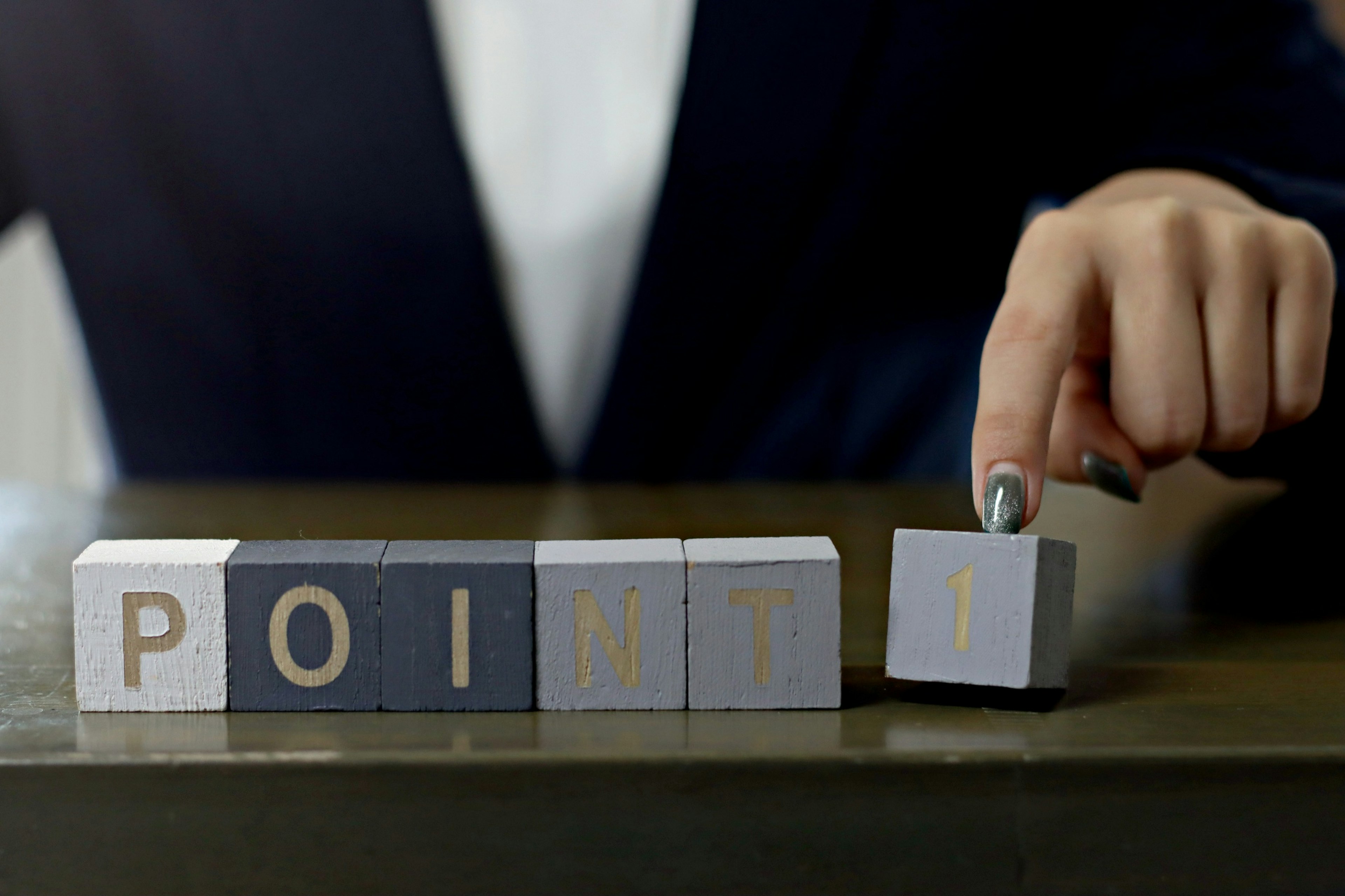 A hand in a business suit is arranging blocks to display POINT 1