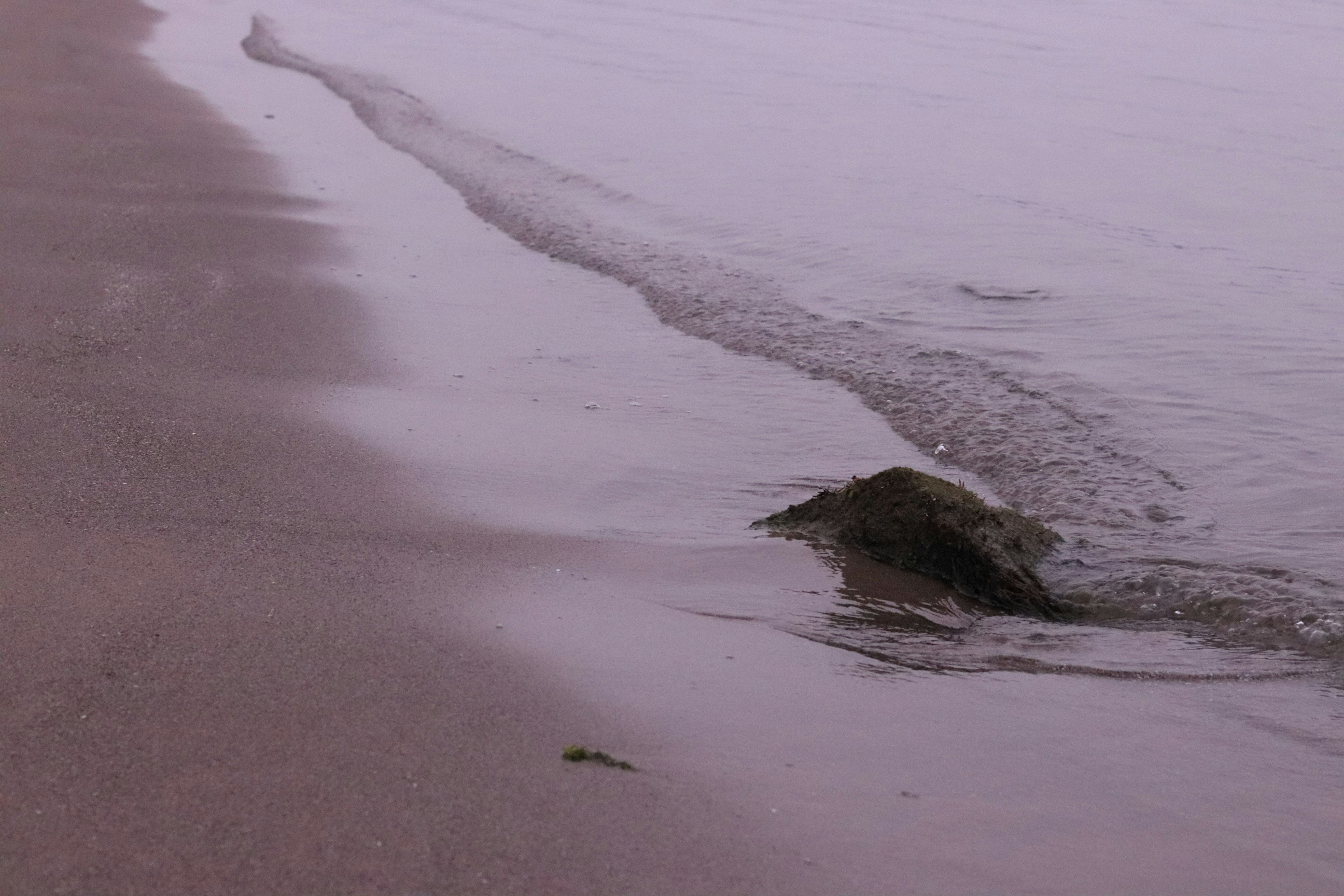 Ruhiger Strand mit Sand und Wellen, die sich treffen