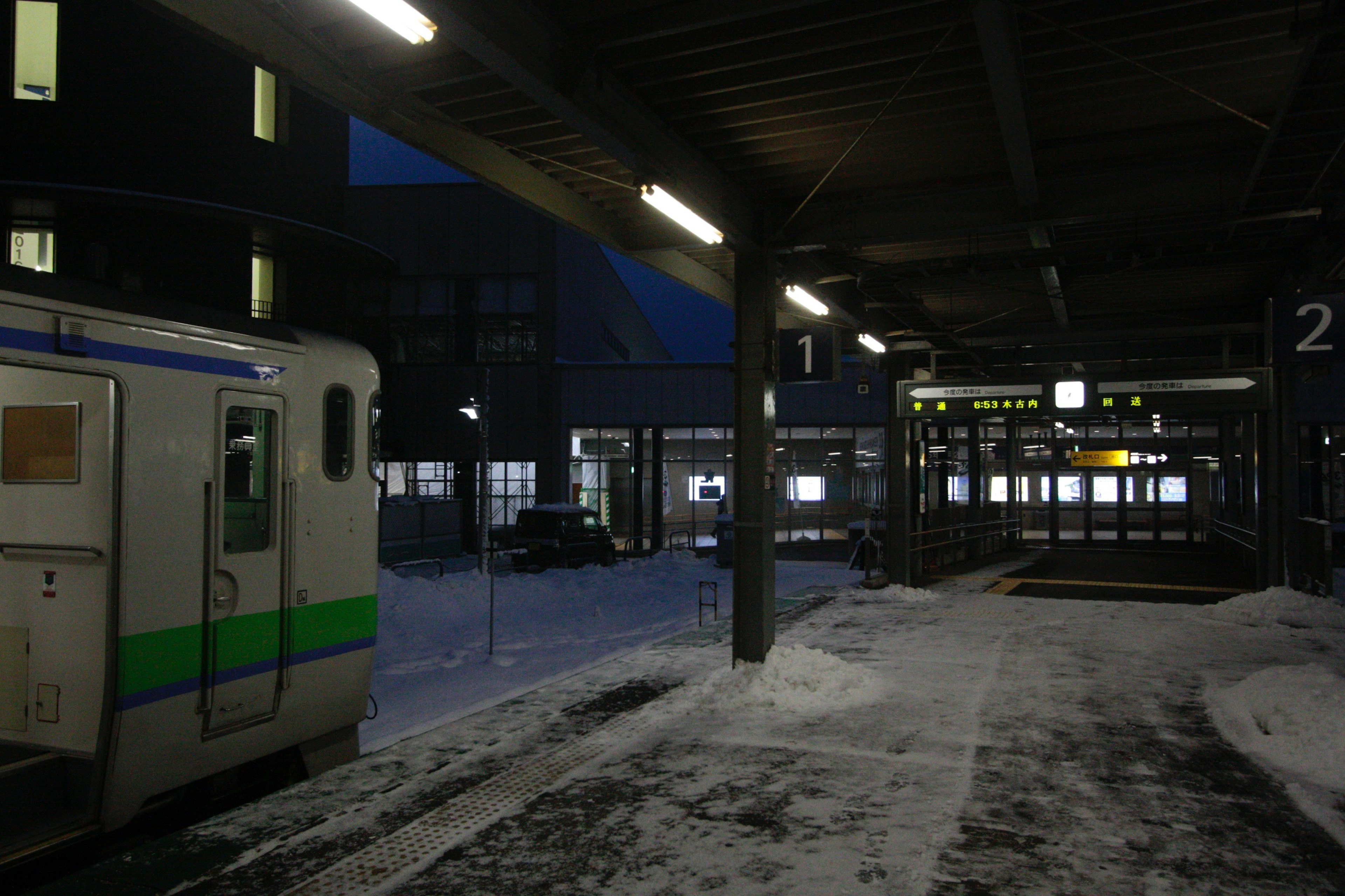 Zug auf einem verschneiten Bahnsteig mit dunklem Himmel im Hintergrund