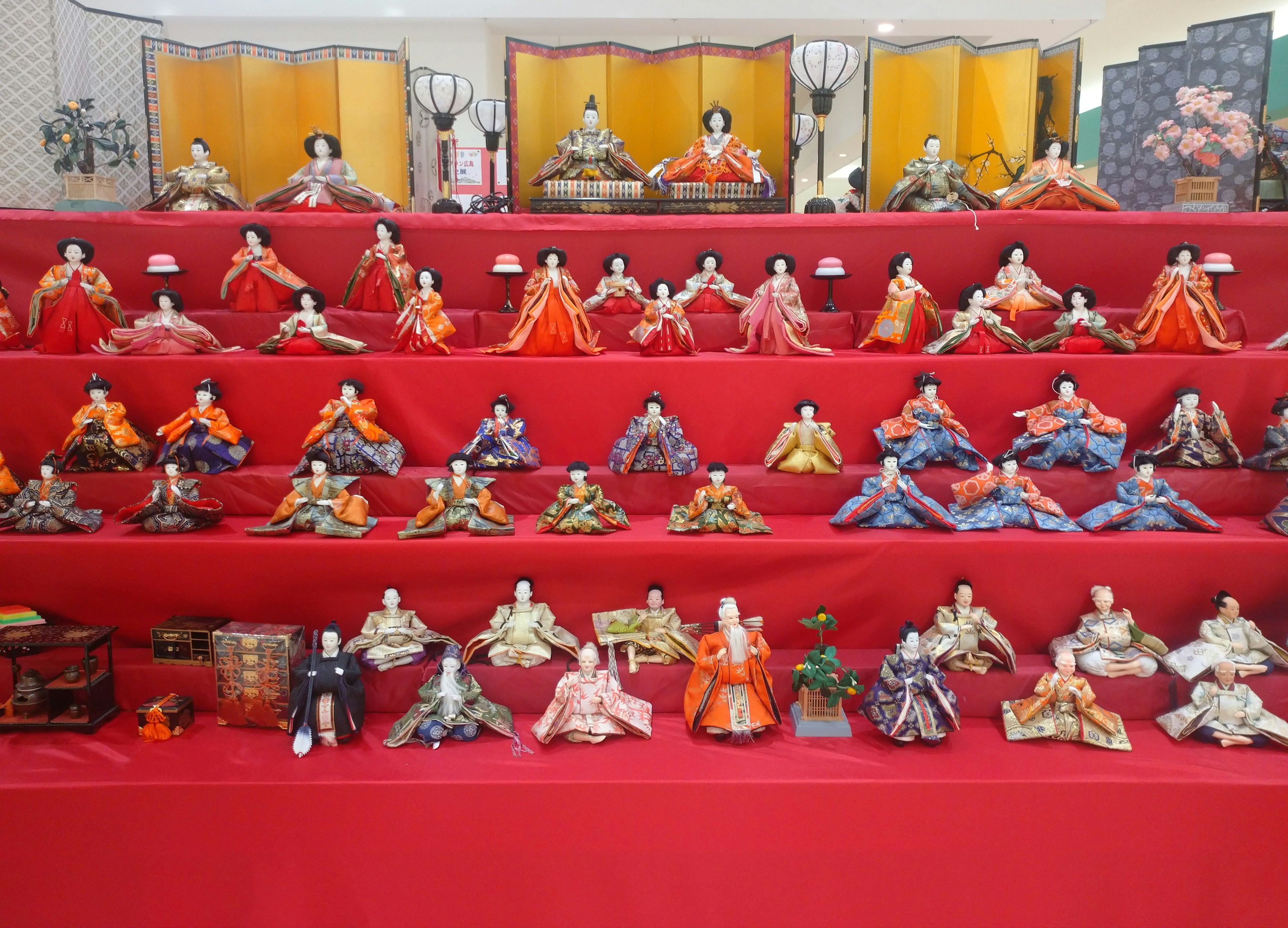 Exposition de diverses poupées disposées sur une table rouge mettant en avant des designs complexes