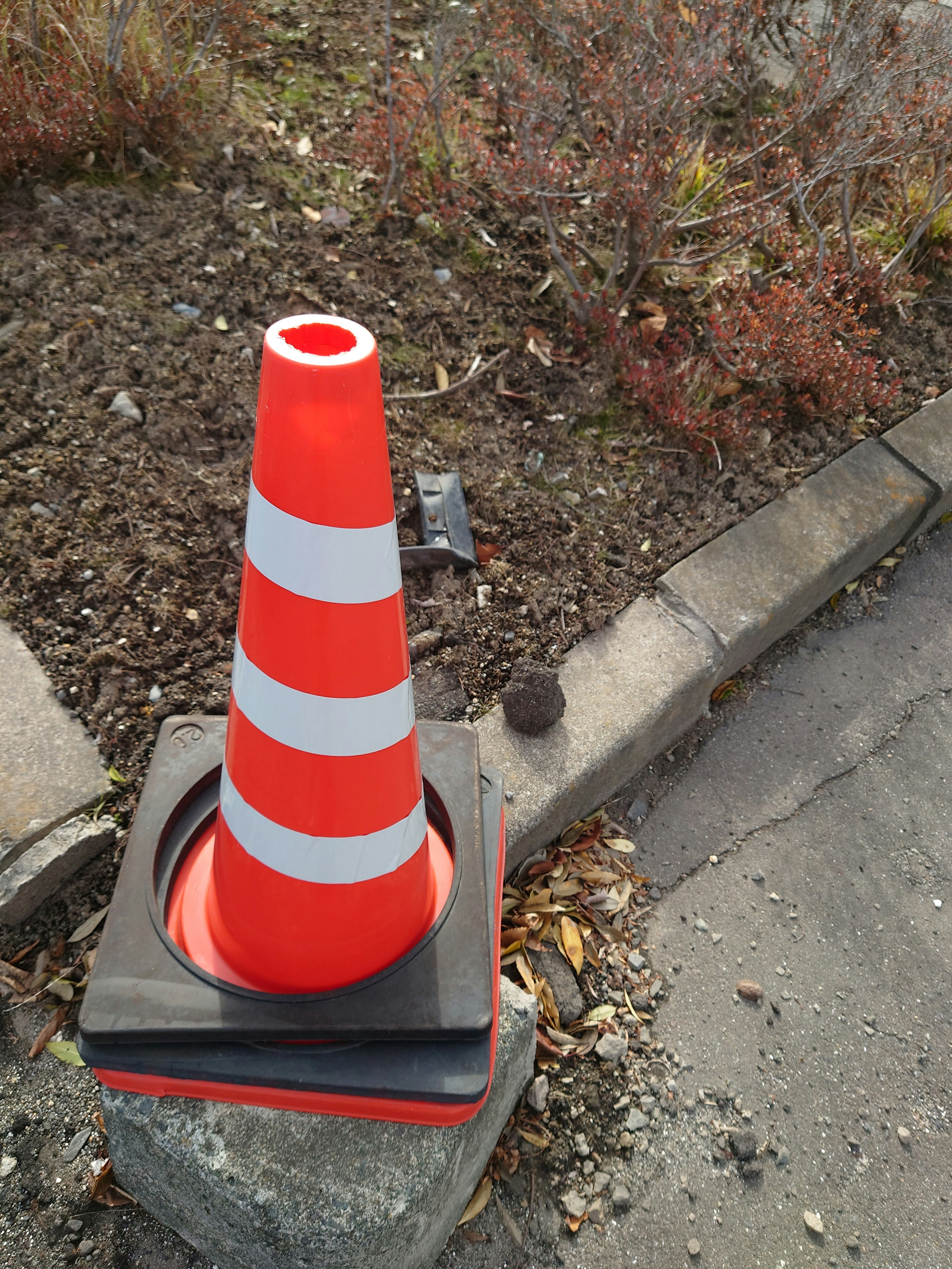 Orange and white striped traffic cone standing on the ground