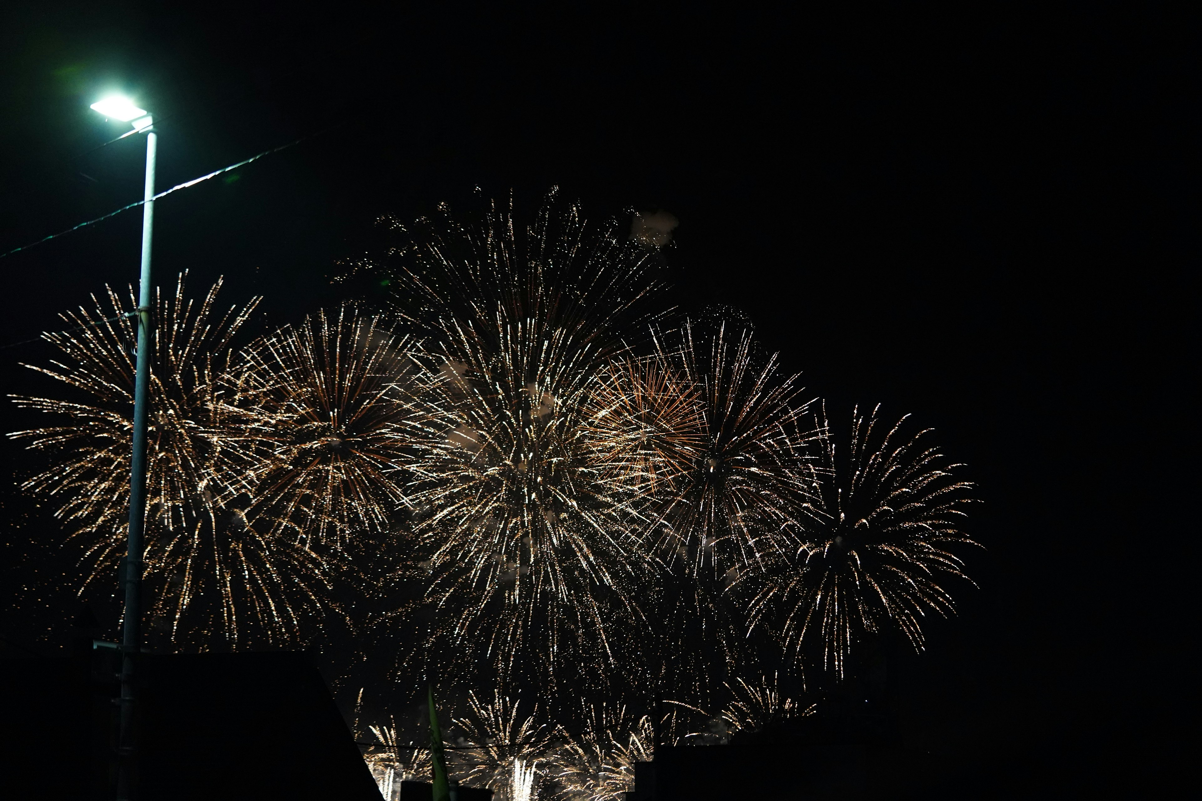 Espectáculo de fuegos artificiales vibrantes en el cielo nocturno con una farola