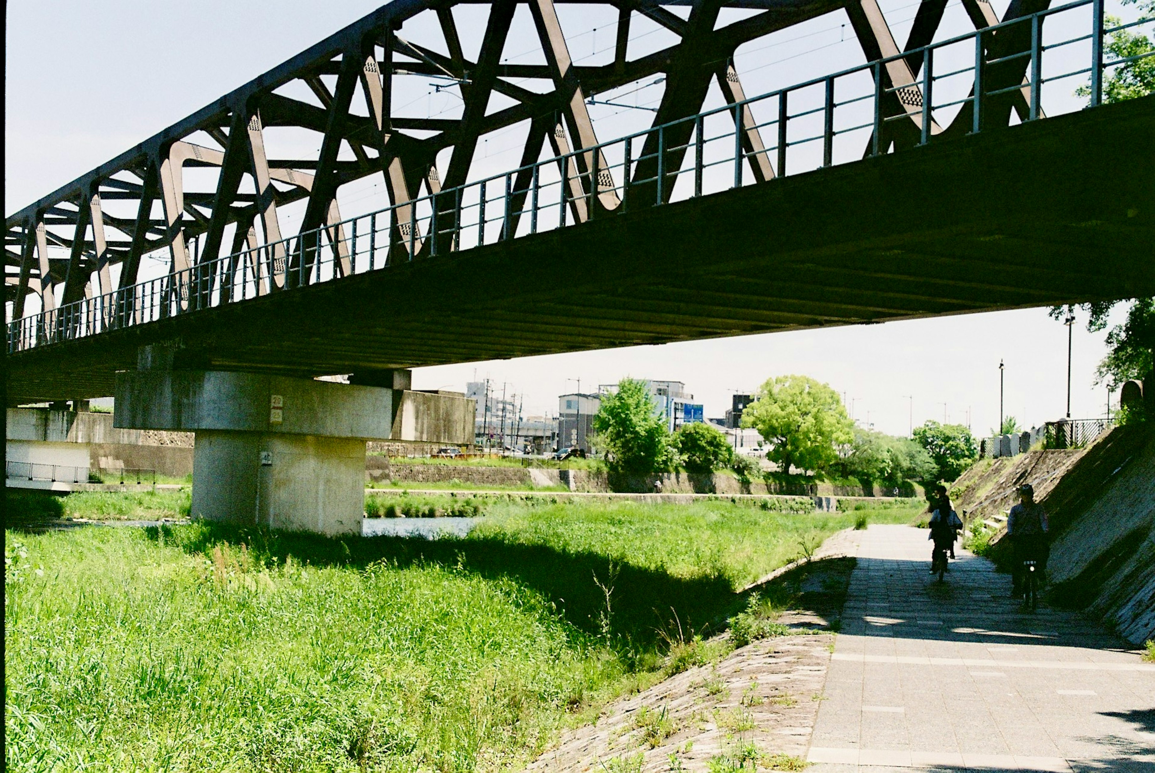 一座鐵路橋橫跨在河上，周圍是郁郁蔥蔥的綠地和鋪好的步道