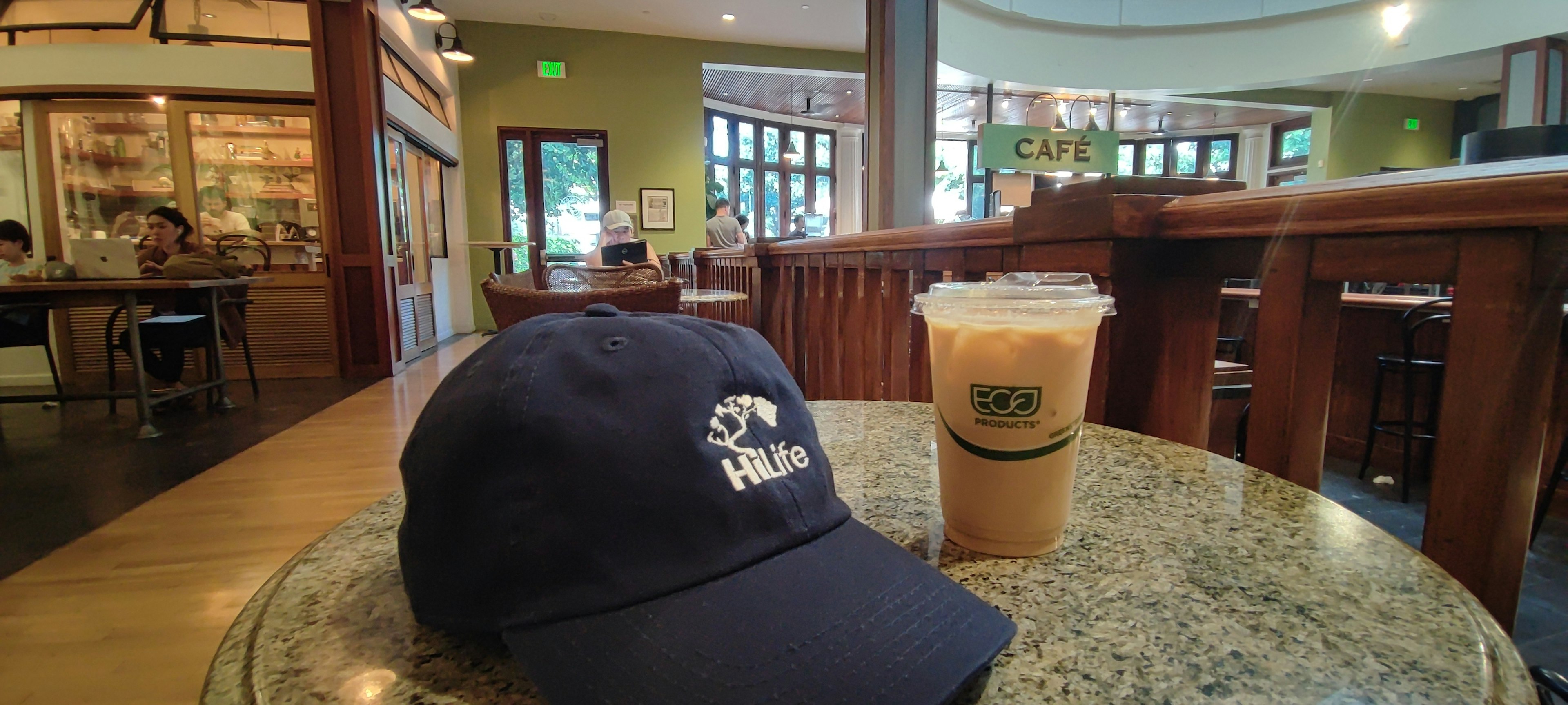 Blaue Baseballmütze und Eiskaffee auf einem Café-Tisch