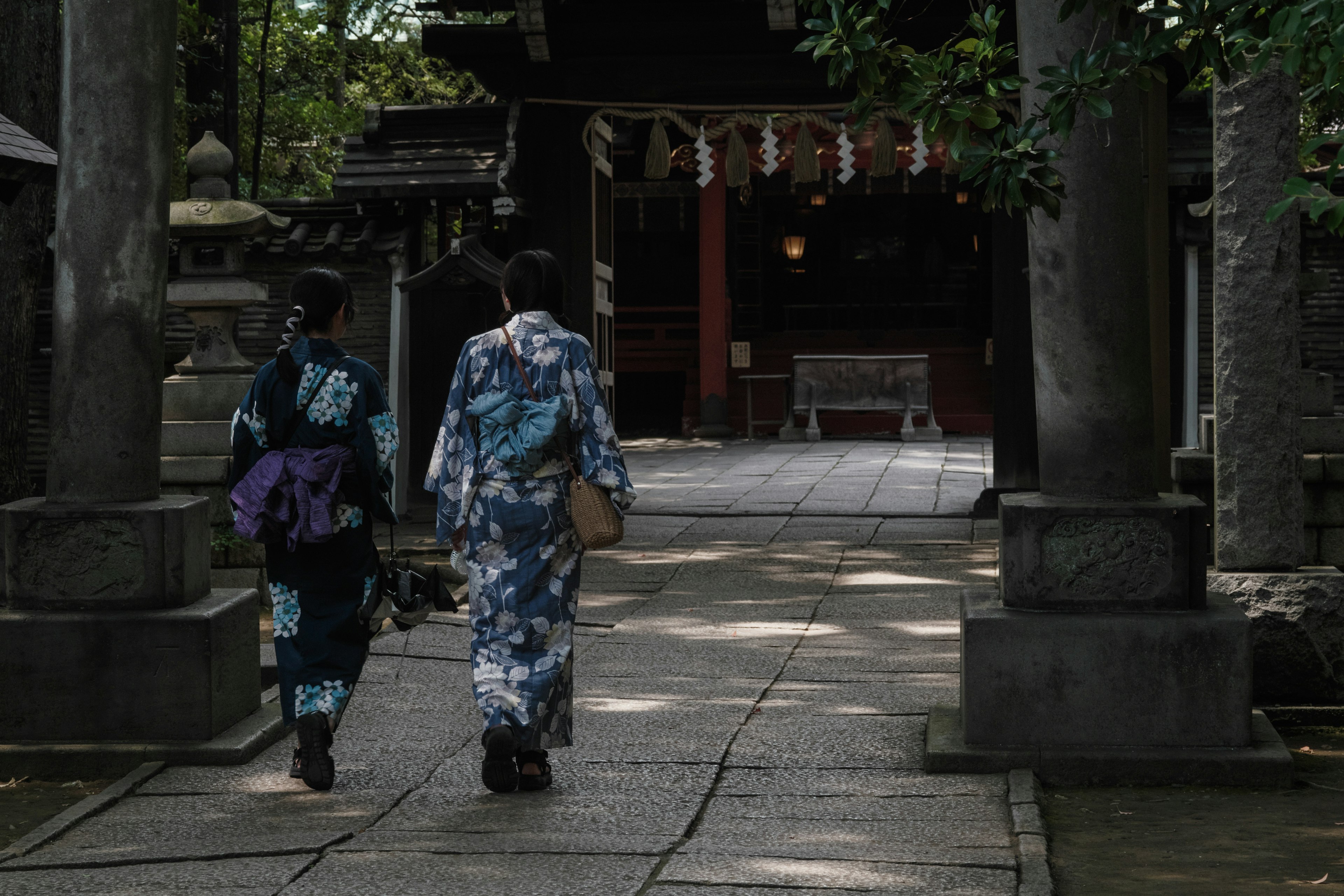 Due donne in kimono che camminano lungo un sentiero in un santuario