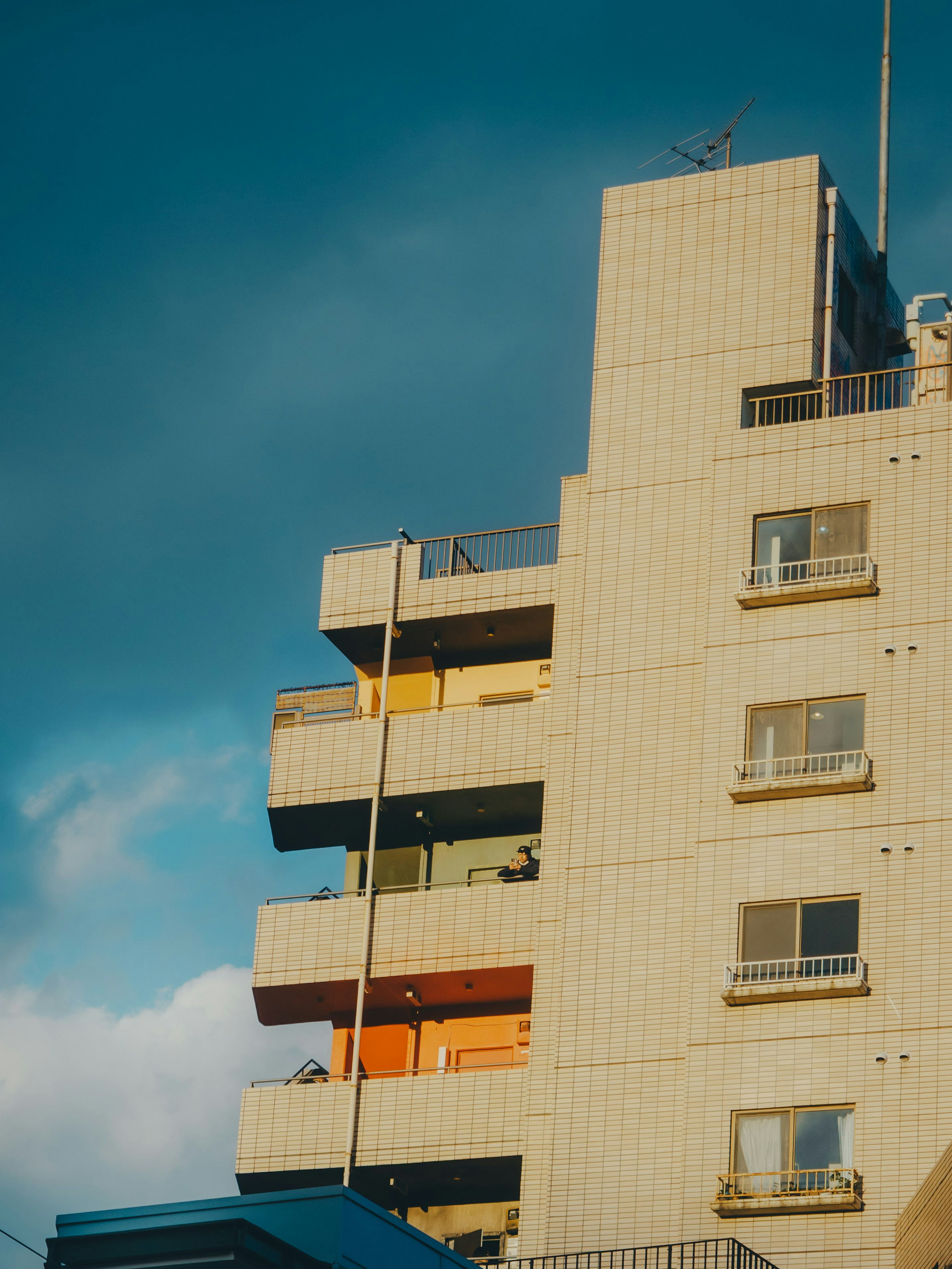 Gedung apartemen modern di bawah langit biru dengan balkon berwarna-warni