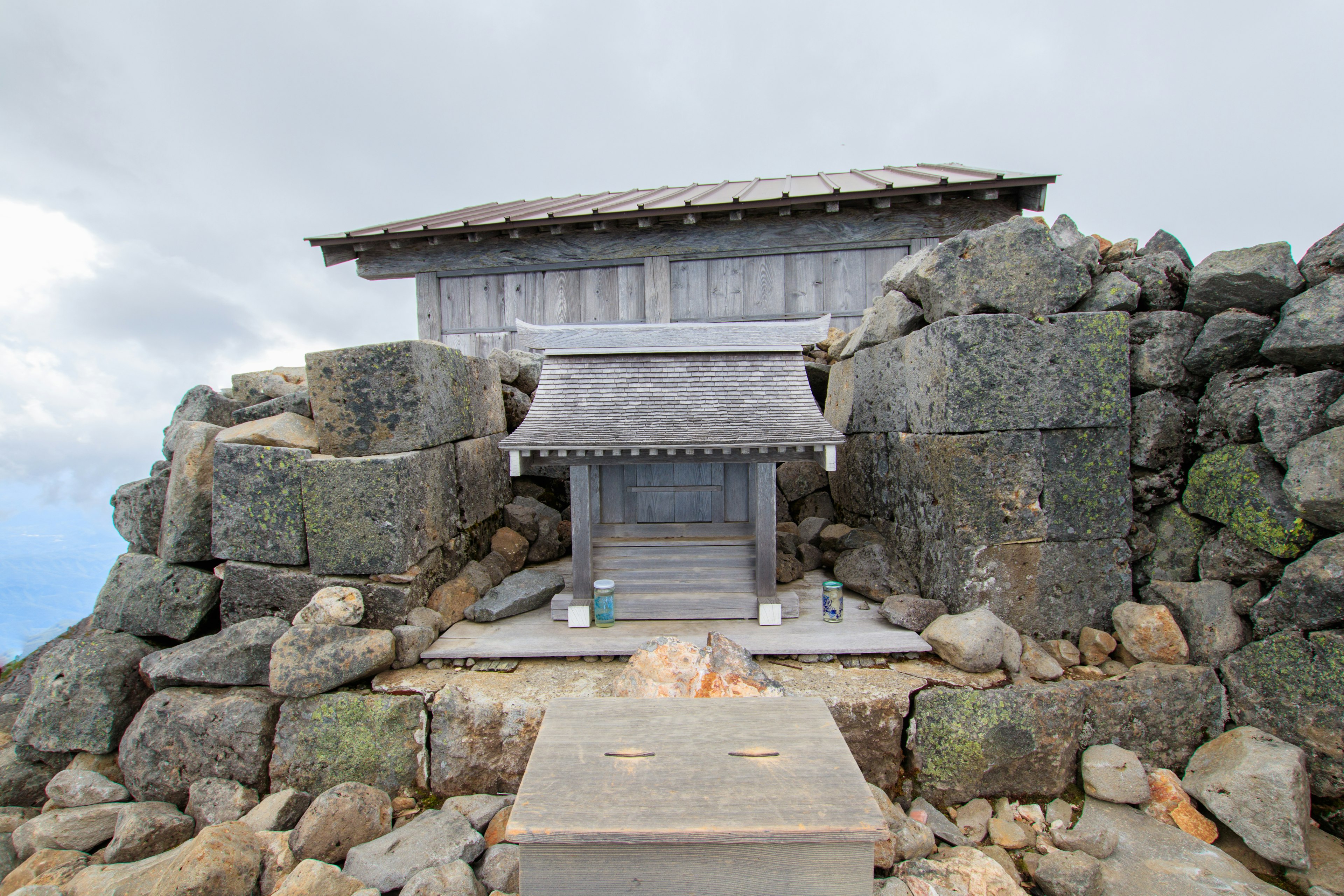 Traditionelles Schreingebäude auf dem Berggipfel umgeben von großen Steinen