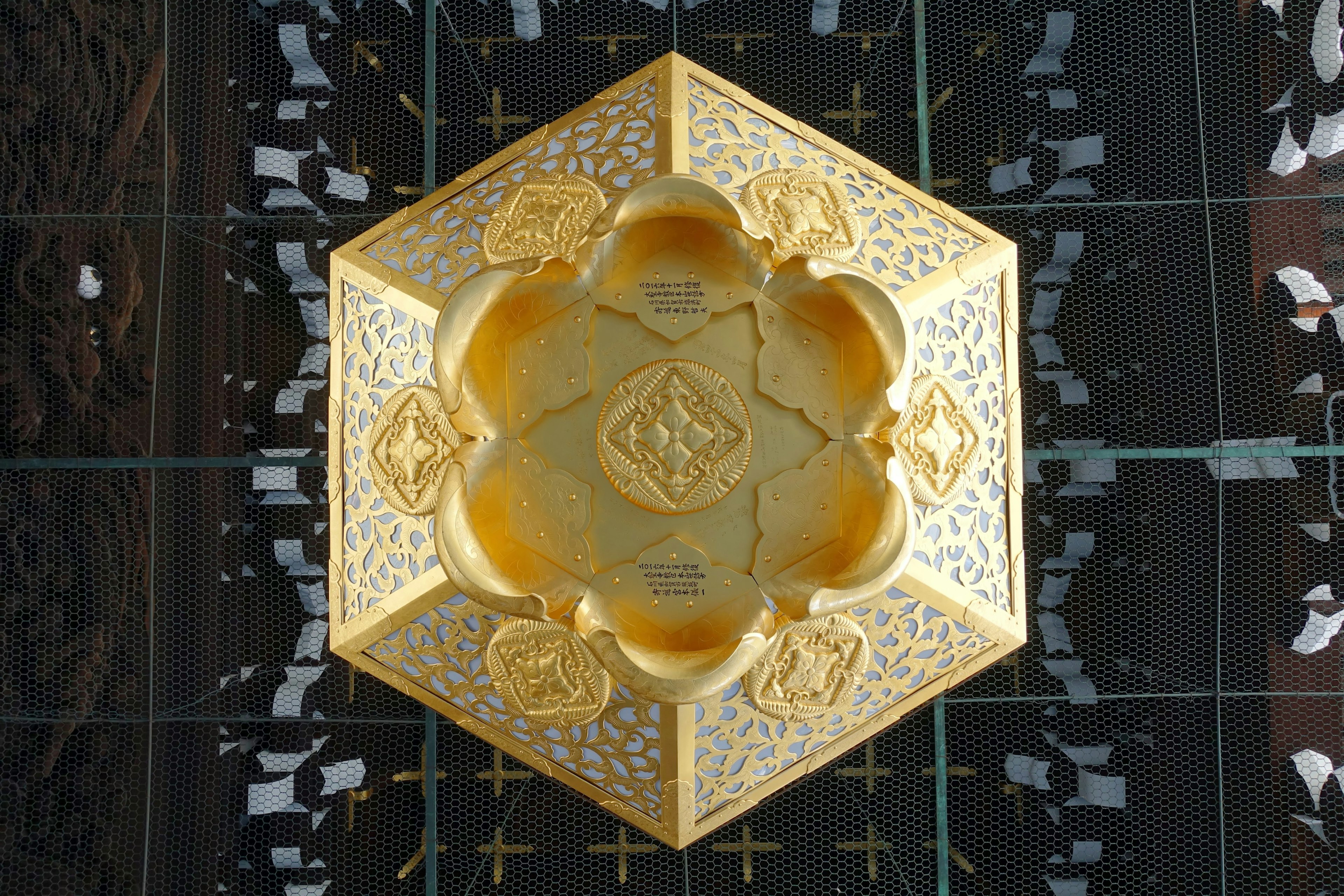 Top view of a decorative hexagonal golden dish featuring intricate patterns and shine