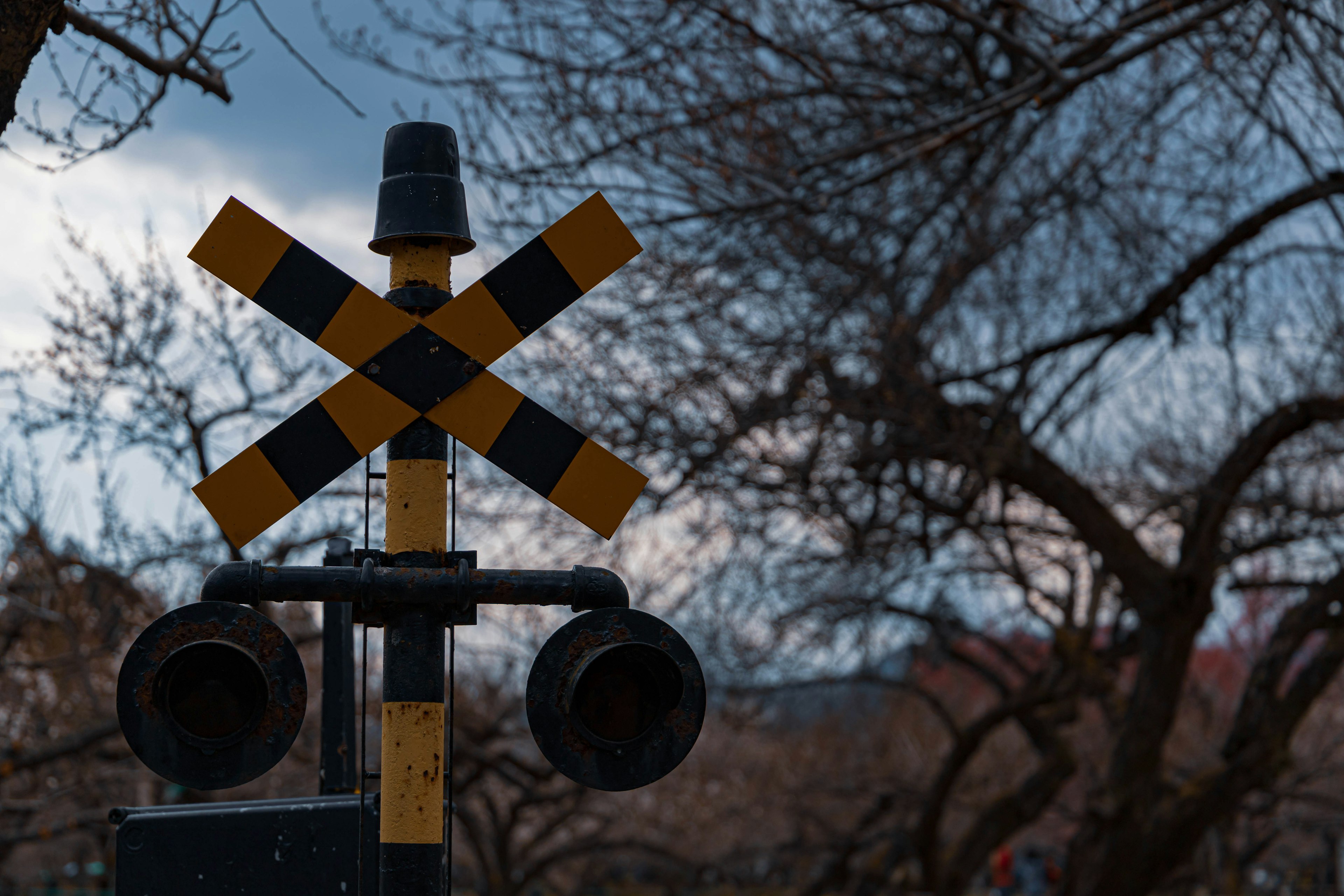 Ein gelbes und schwarzes Bahnübergangsschild mit Signalleuchten