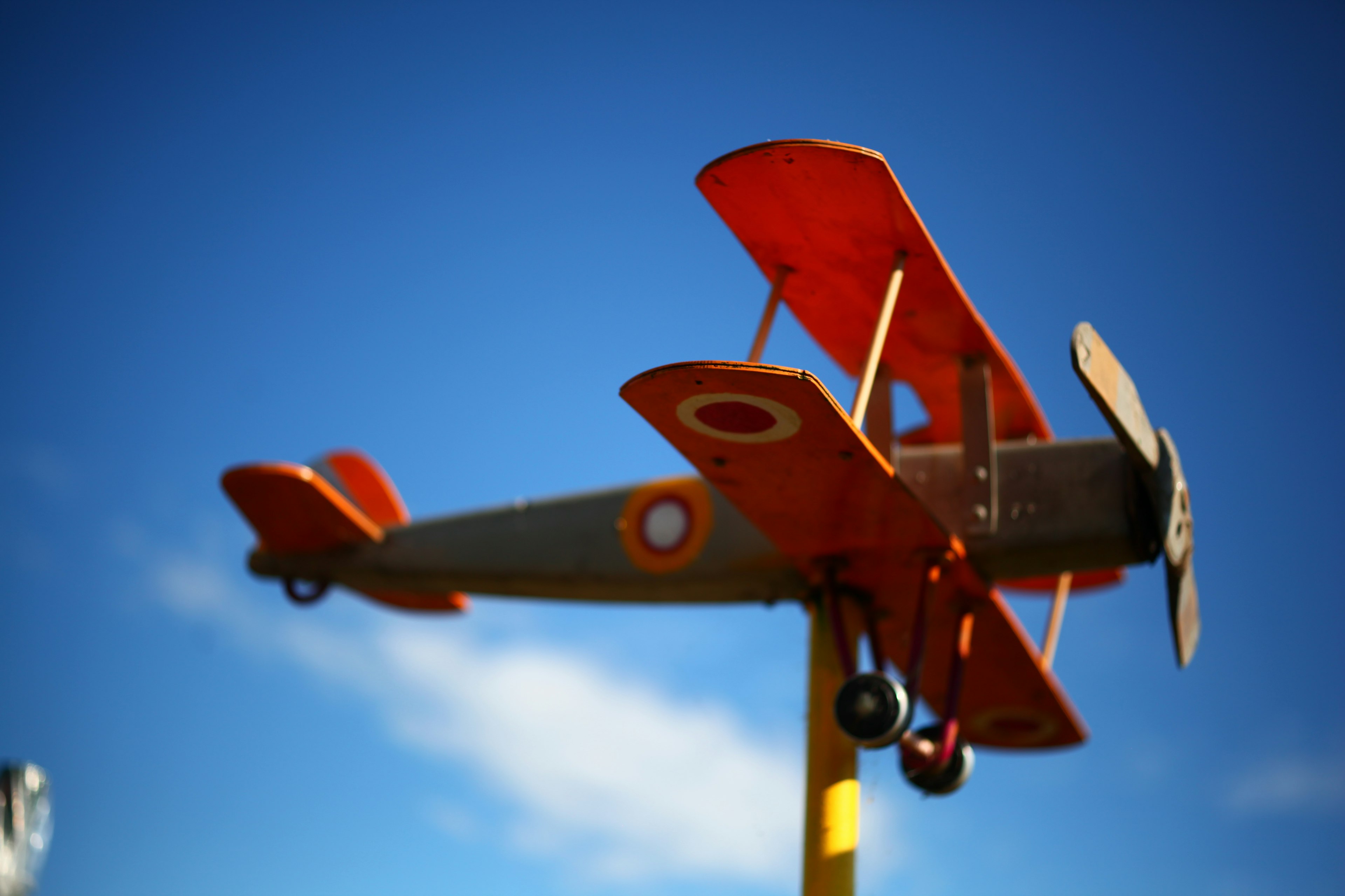 Model pesawat propeller oranye di latar belakang langit biru