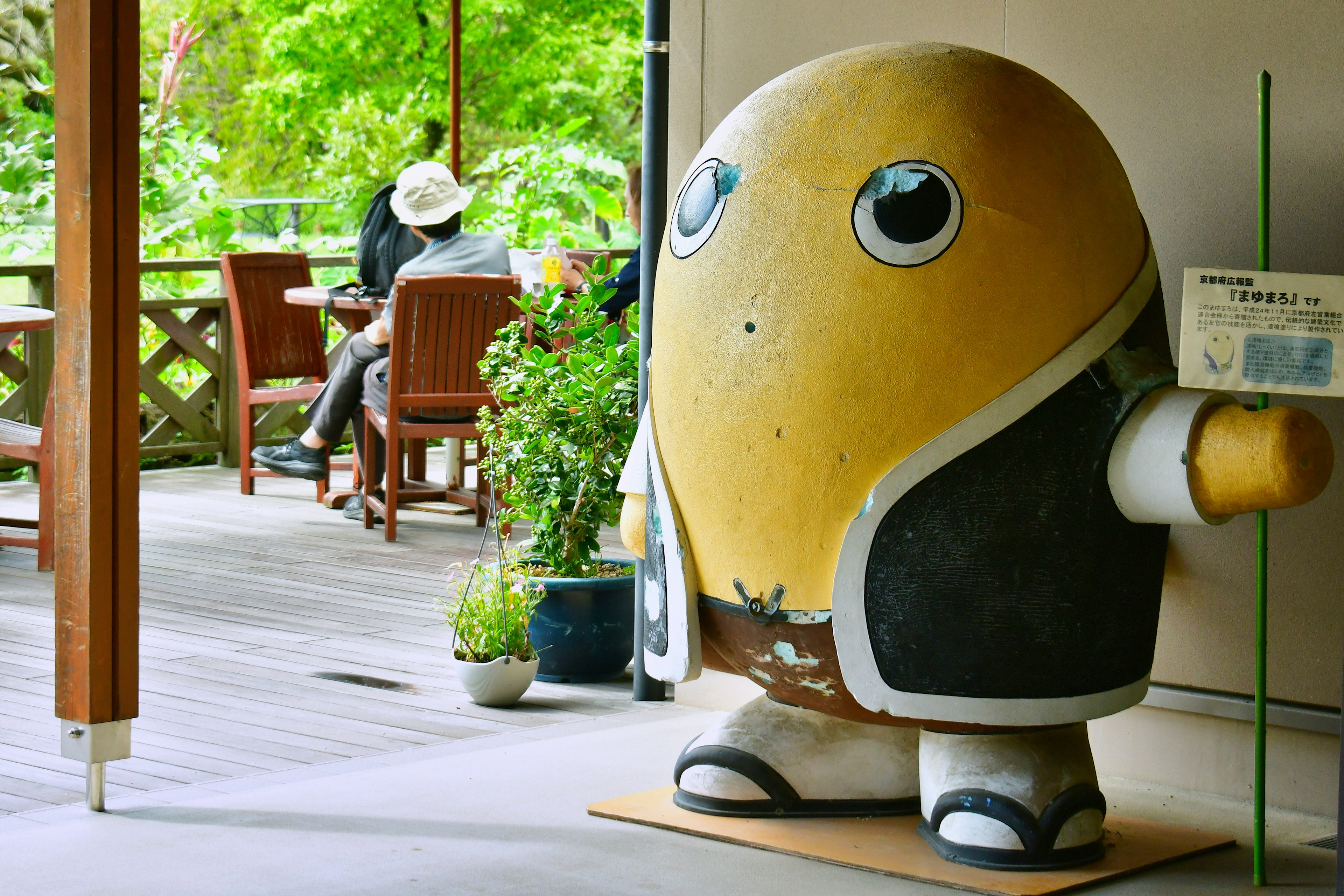 A yellow mascot character standing at the entrance of a shop