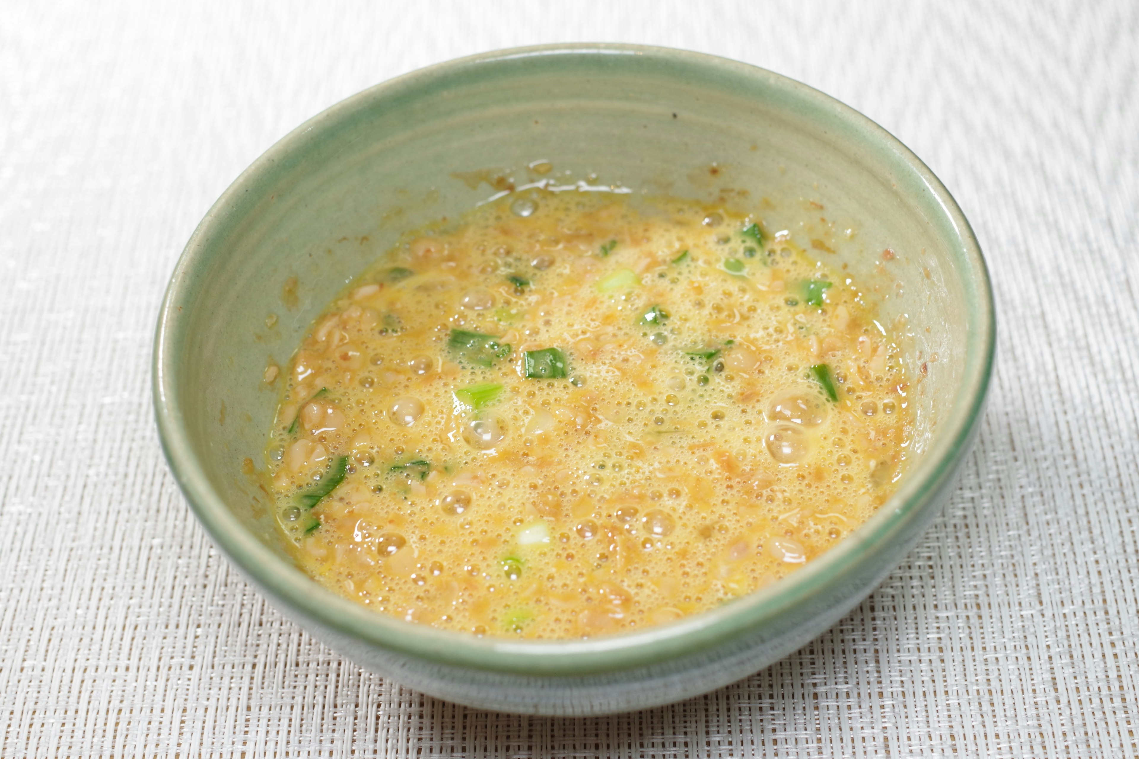 A mixture of eggs and green onions in a green bowl