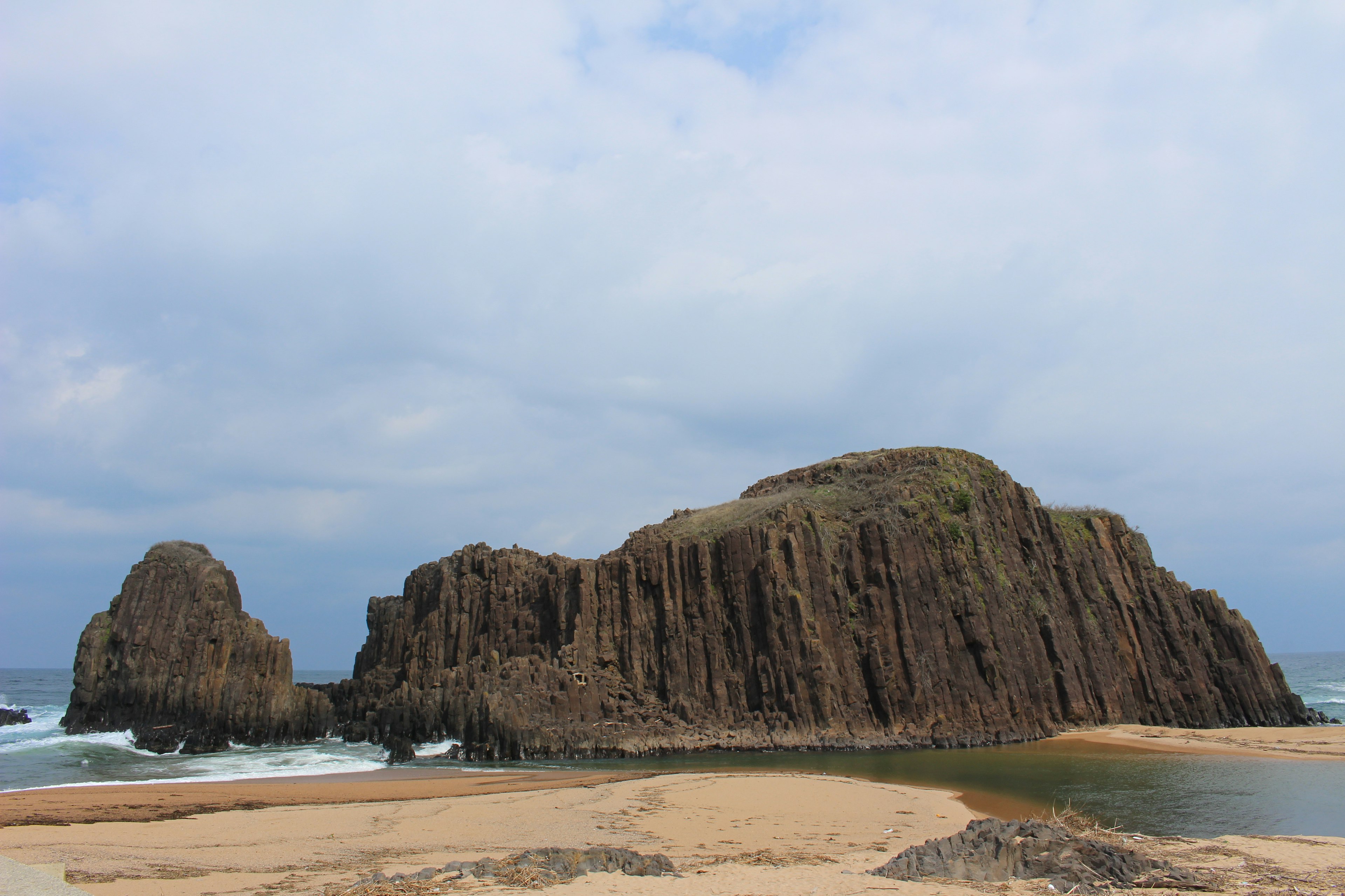 Coastal landscape featuring towering rocks and sandy shore