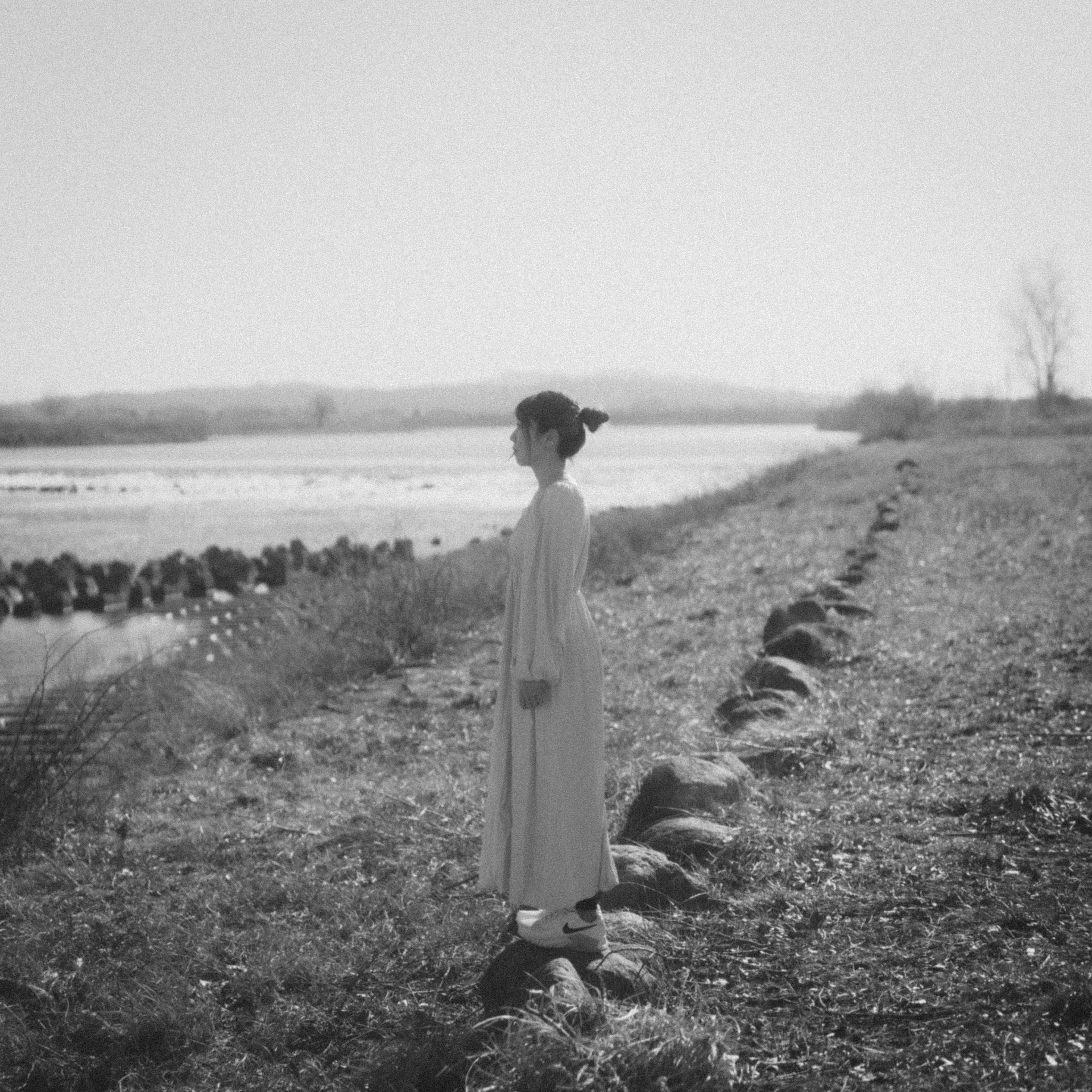 Foto en blanco y negro de una mujer de pie junto al río