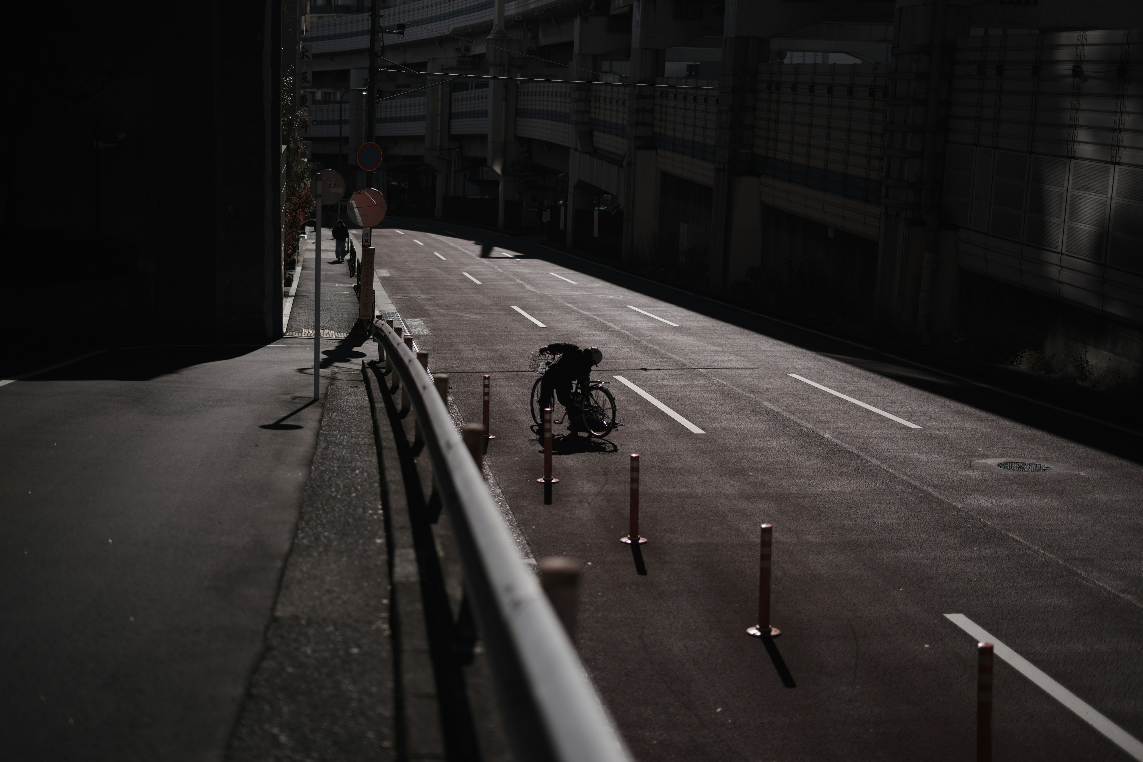 暗い道路で自転車に乗る人とガードレールのシルエット