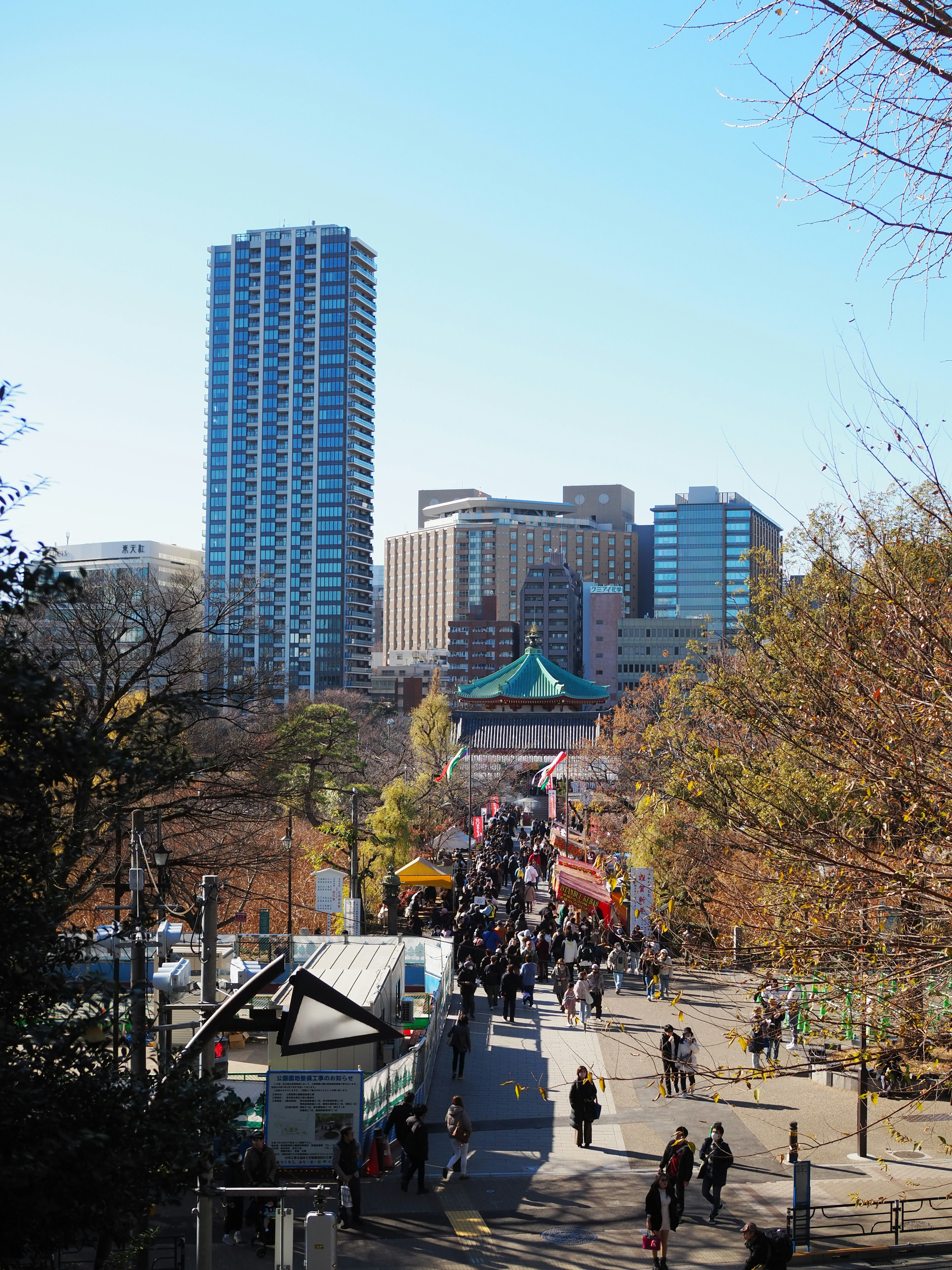 A bustling scene with high-rise buildings and a park filled with people