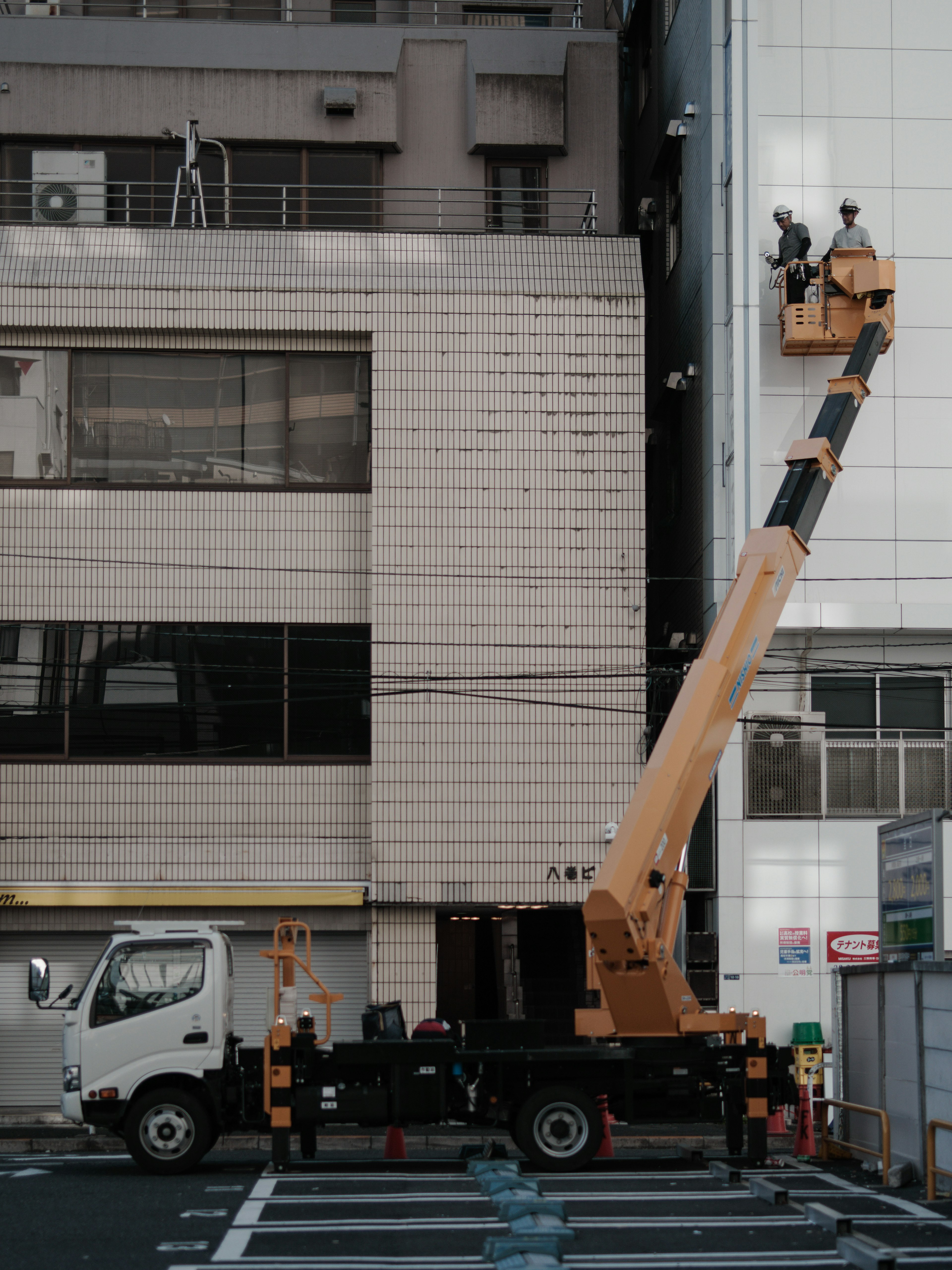 Grúa y trabajadores realizando mantenimiento en la fachada de un edificio