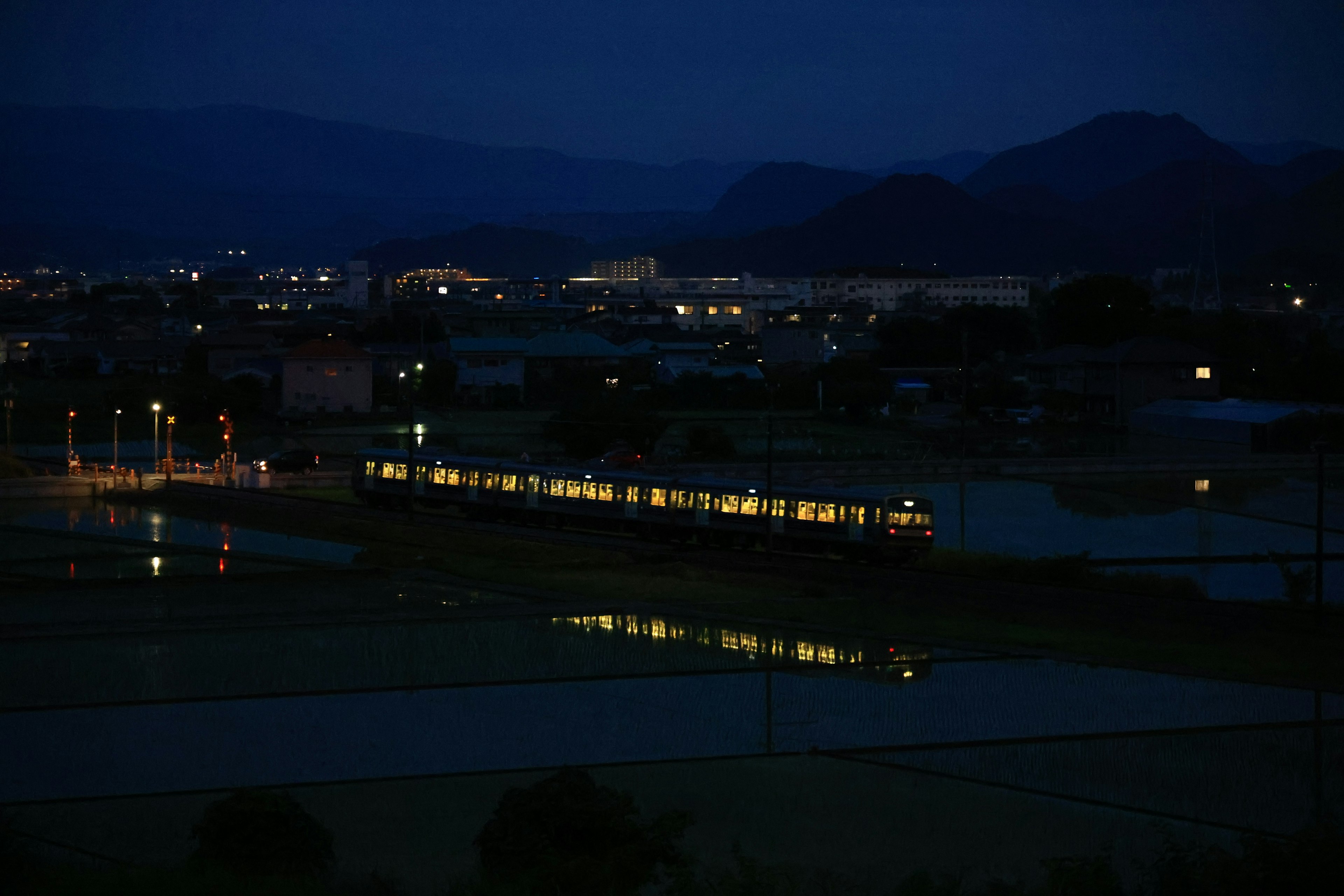 Luces de un tren reflejándose en un paisaje rural de noche