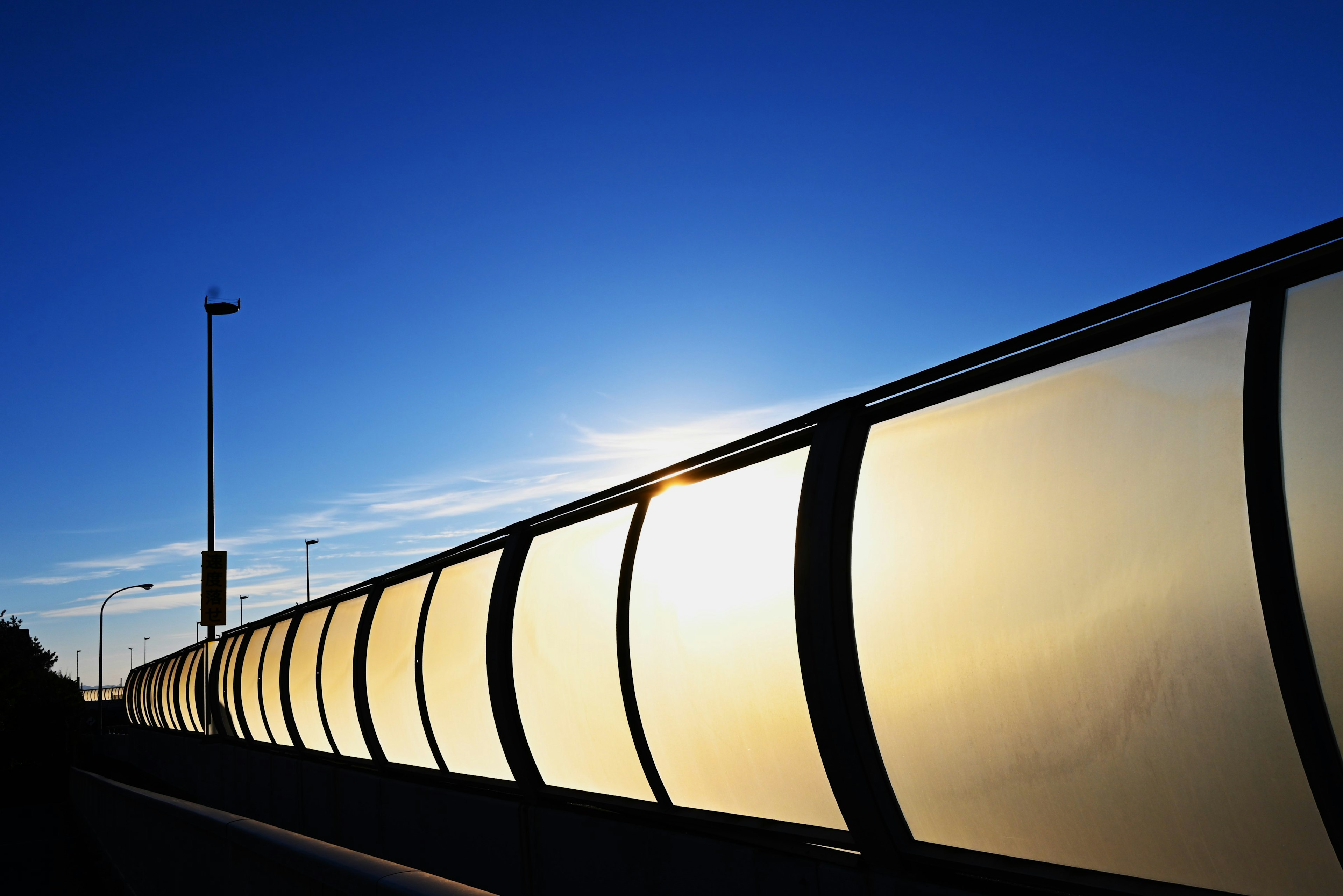 Silhouette of a transparent fence against a blue sky and sunset