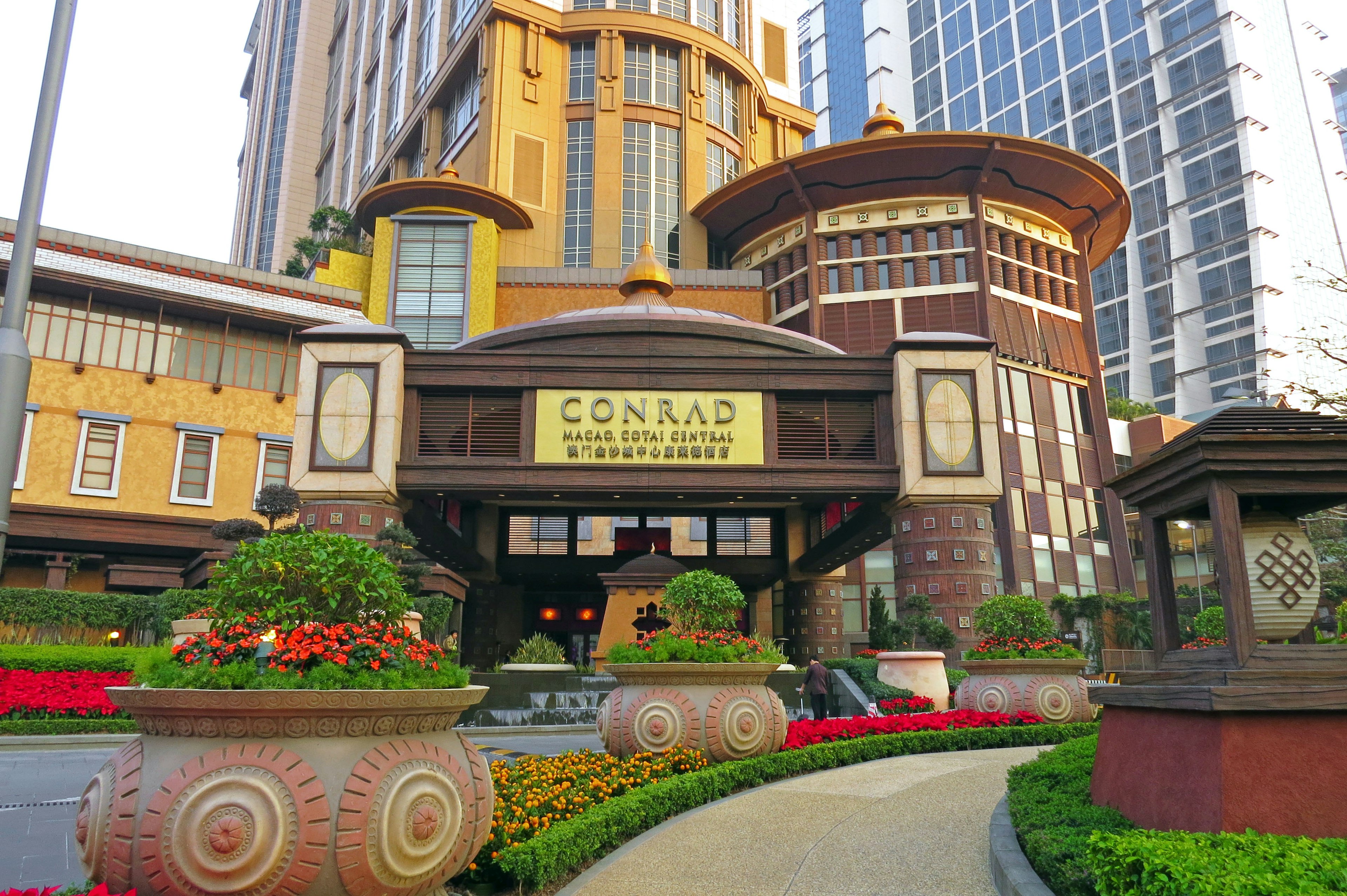 Entrada del Conrad Manila con coloridos parterres de flores