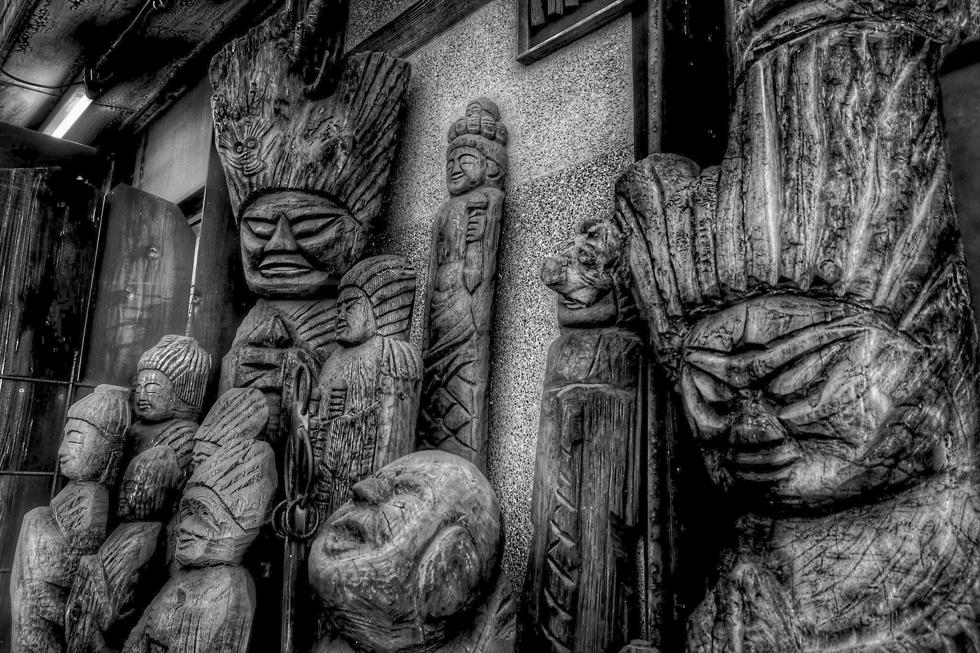 Monochrome image featuring wooden sculptures with diverse facial expressions