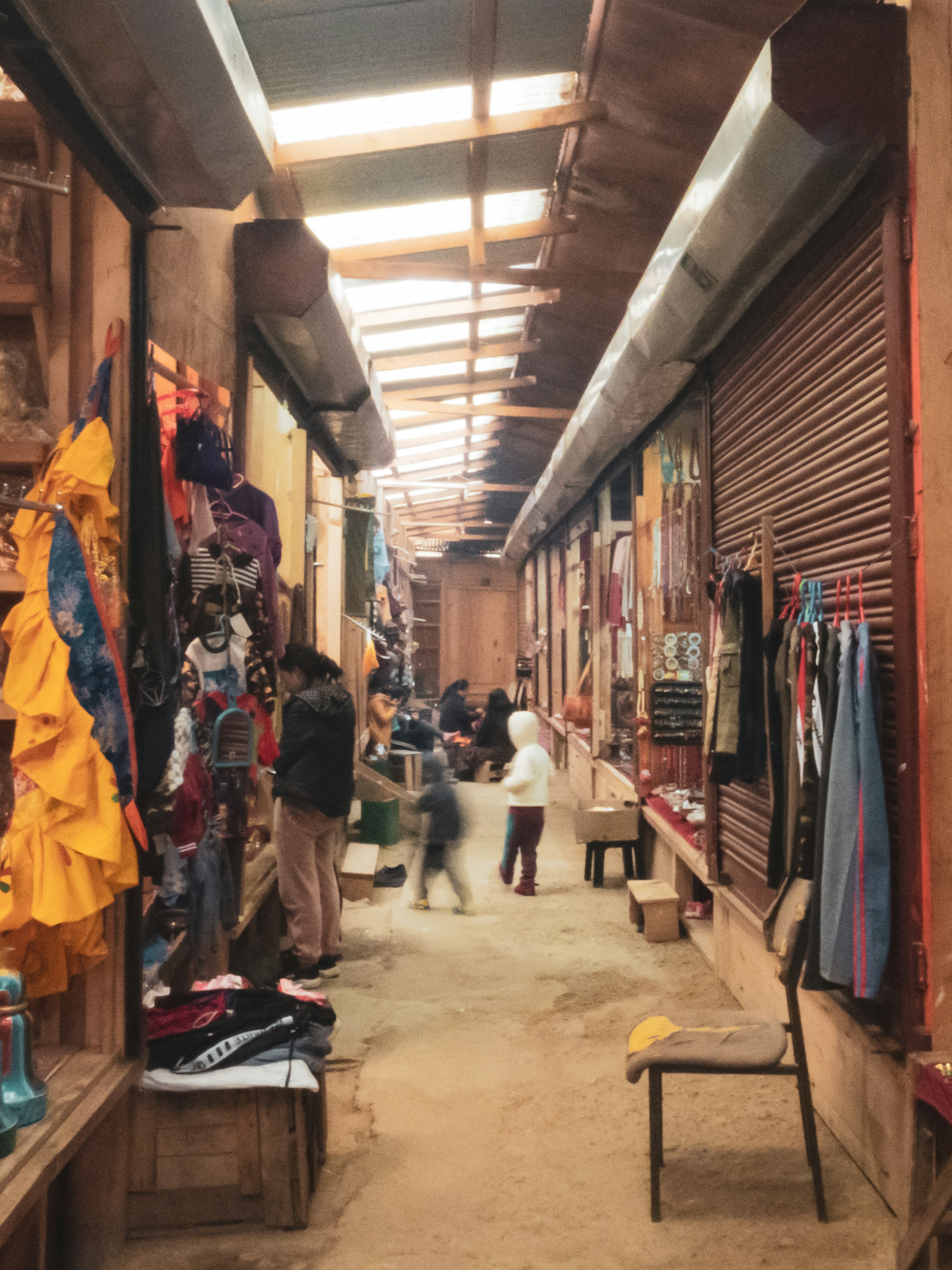 Bustling market alley with colorful fabrics and clothing displayed