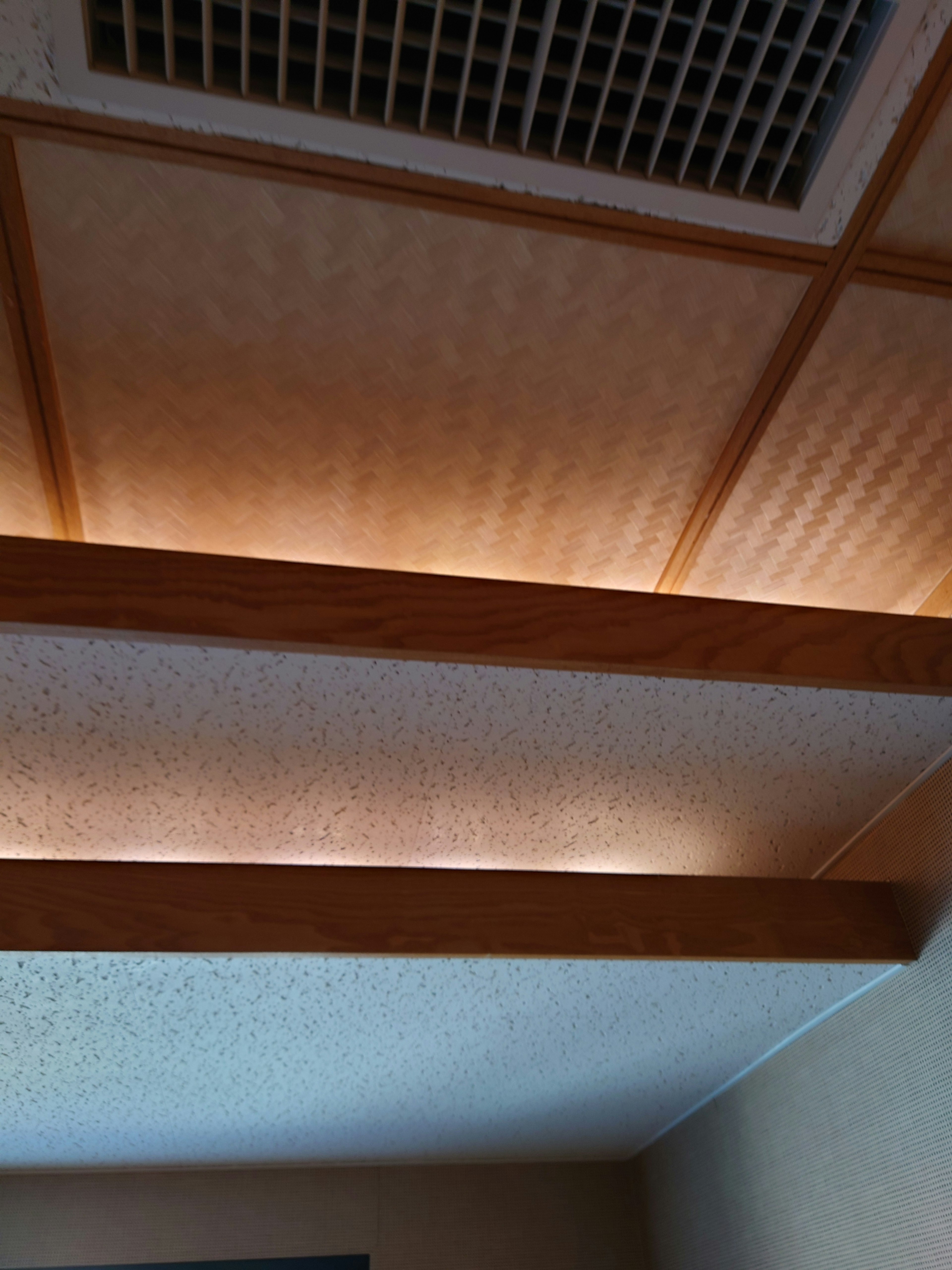 Immagine che mostra un soffitto di una stanza con travi in legno e illuminazione calda e morbida