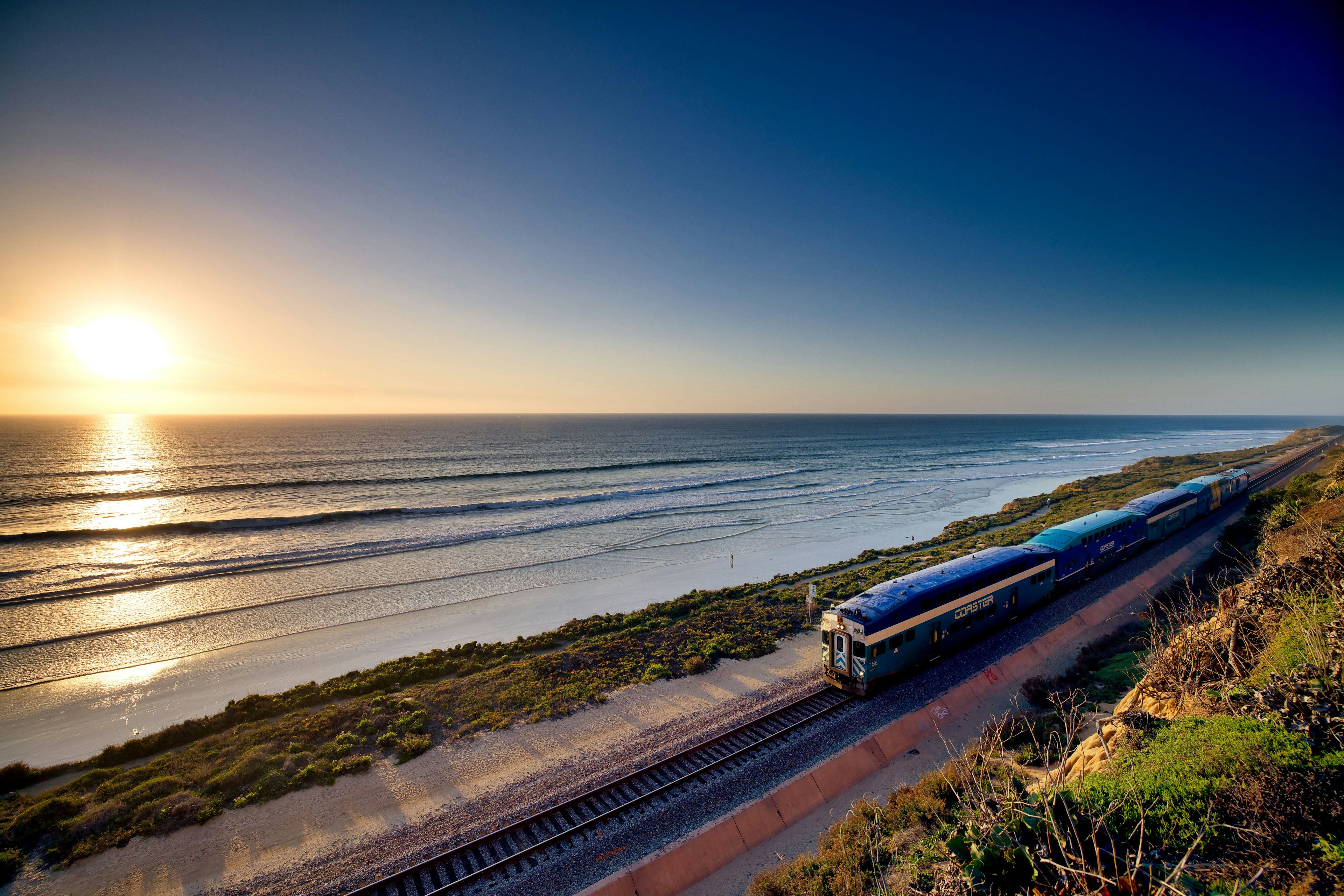 Vista escénica de un tren a lo largo de la costa al atardecer