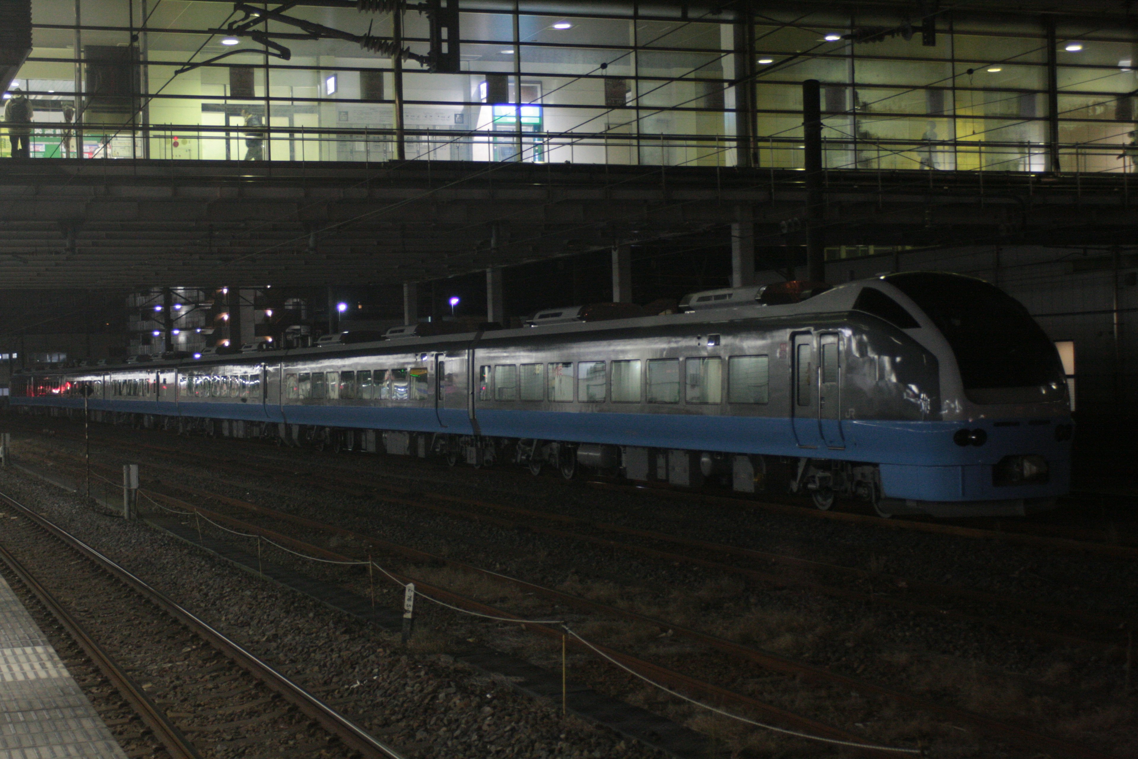 Sebuah kereta biru diparkir di stasiun pada malam hari