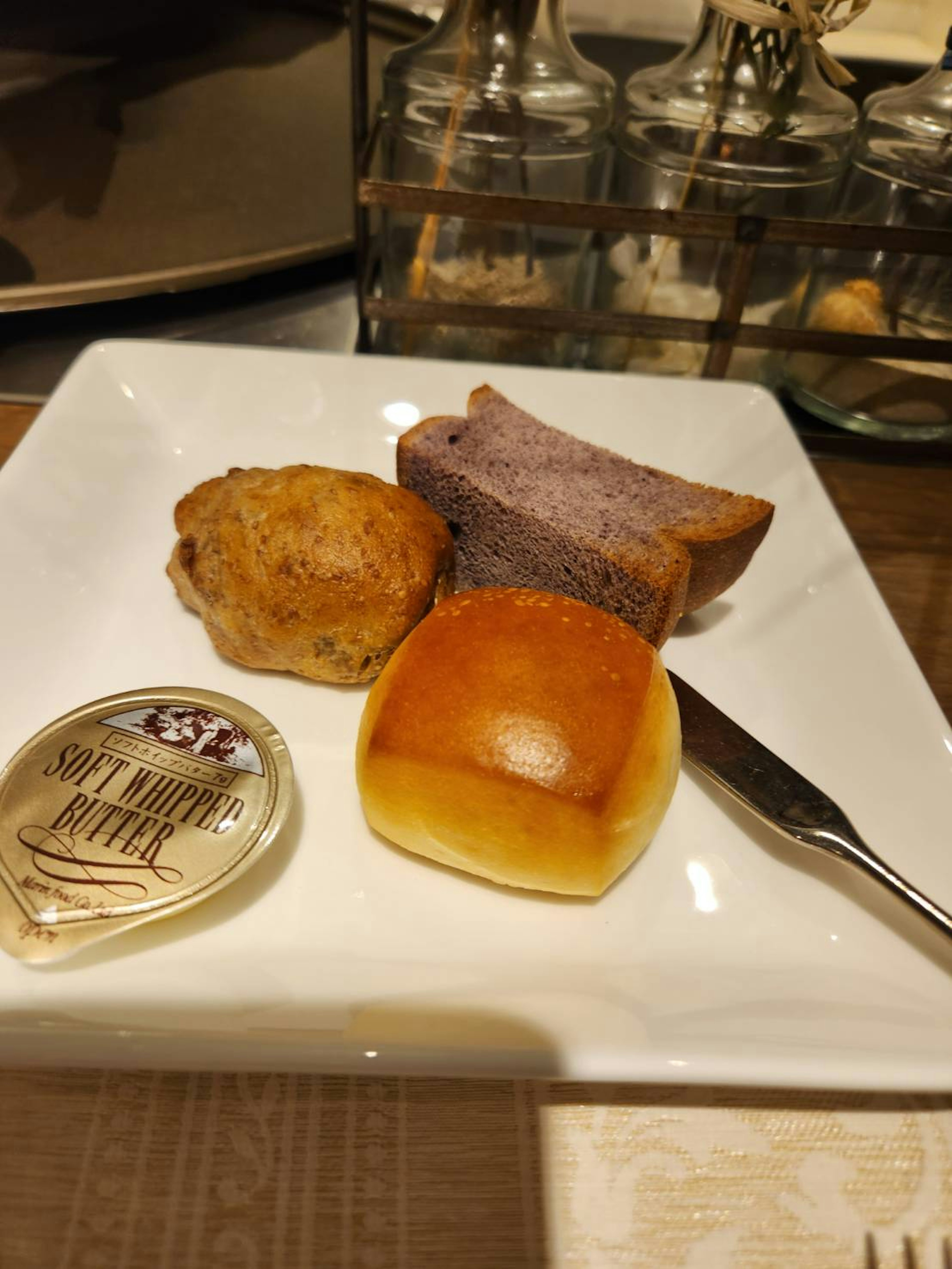 A plate with assorted breads including a roll and a muffin