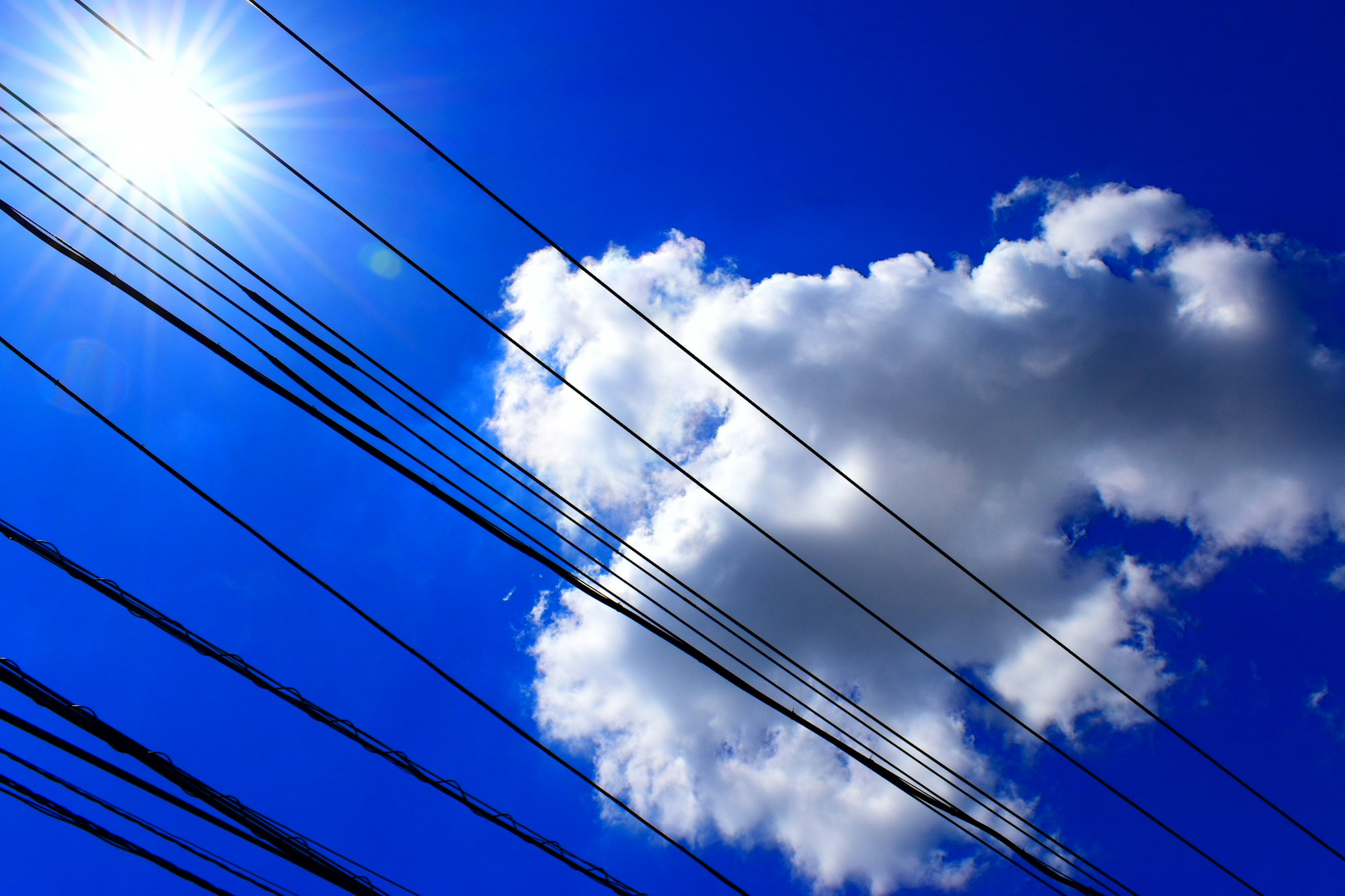 Photo of white clouds and power lines against a blue sky