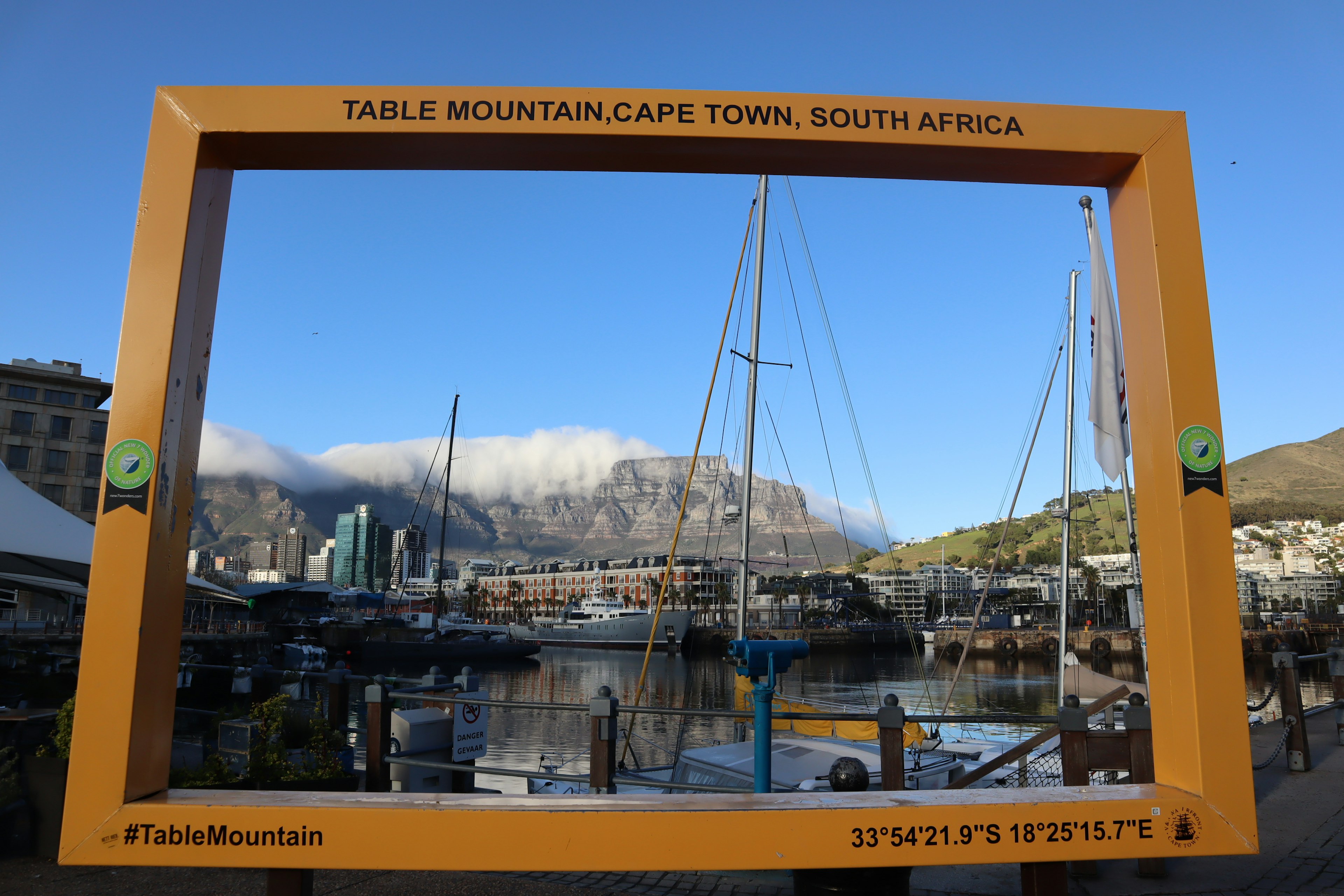 View of Table Mountain with yachts in the harbor framed by a large orange border