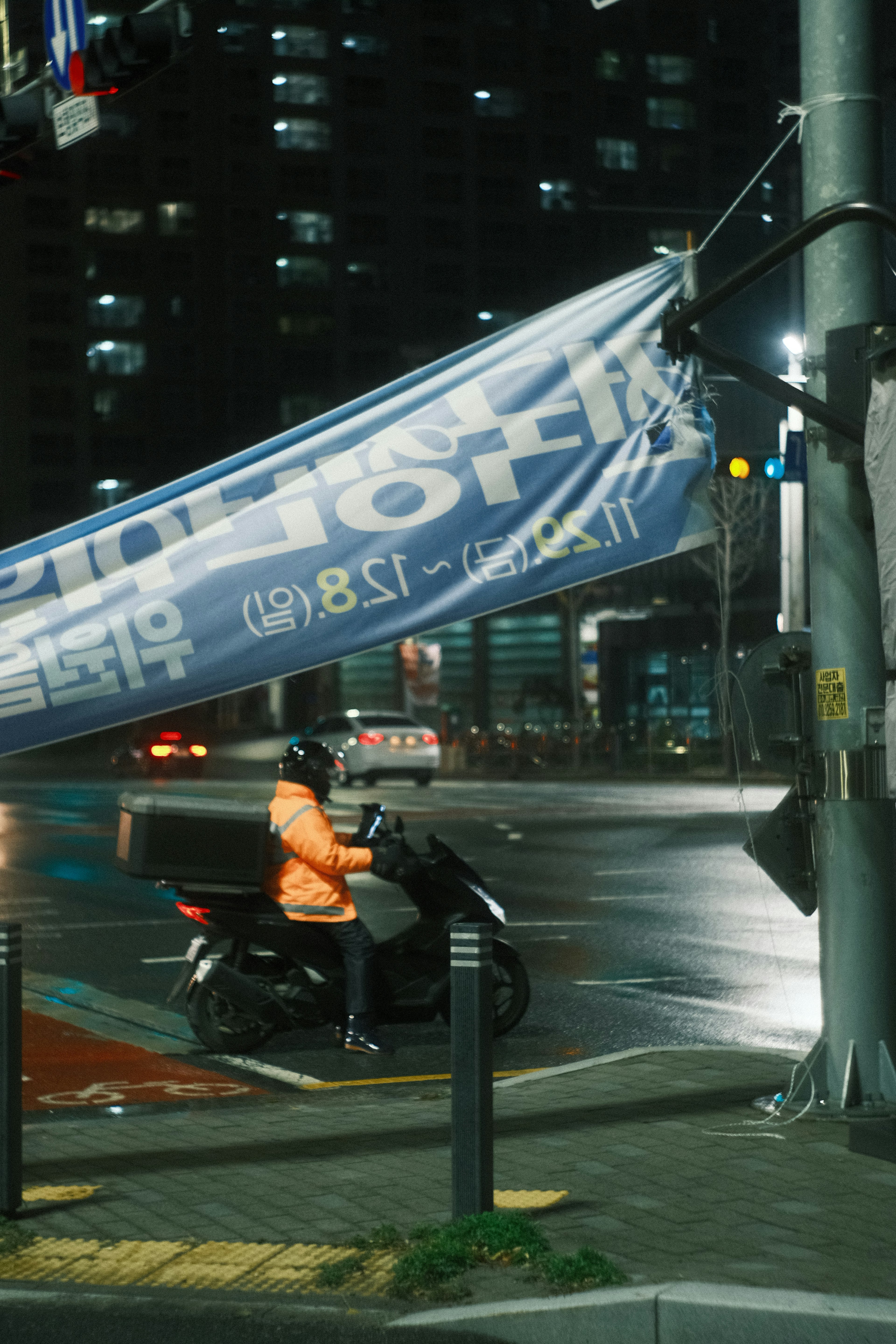 夜の交差点でオレンジのジャケットを着たライダーがバイクに乗っている