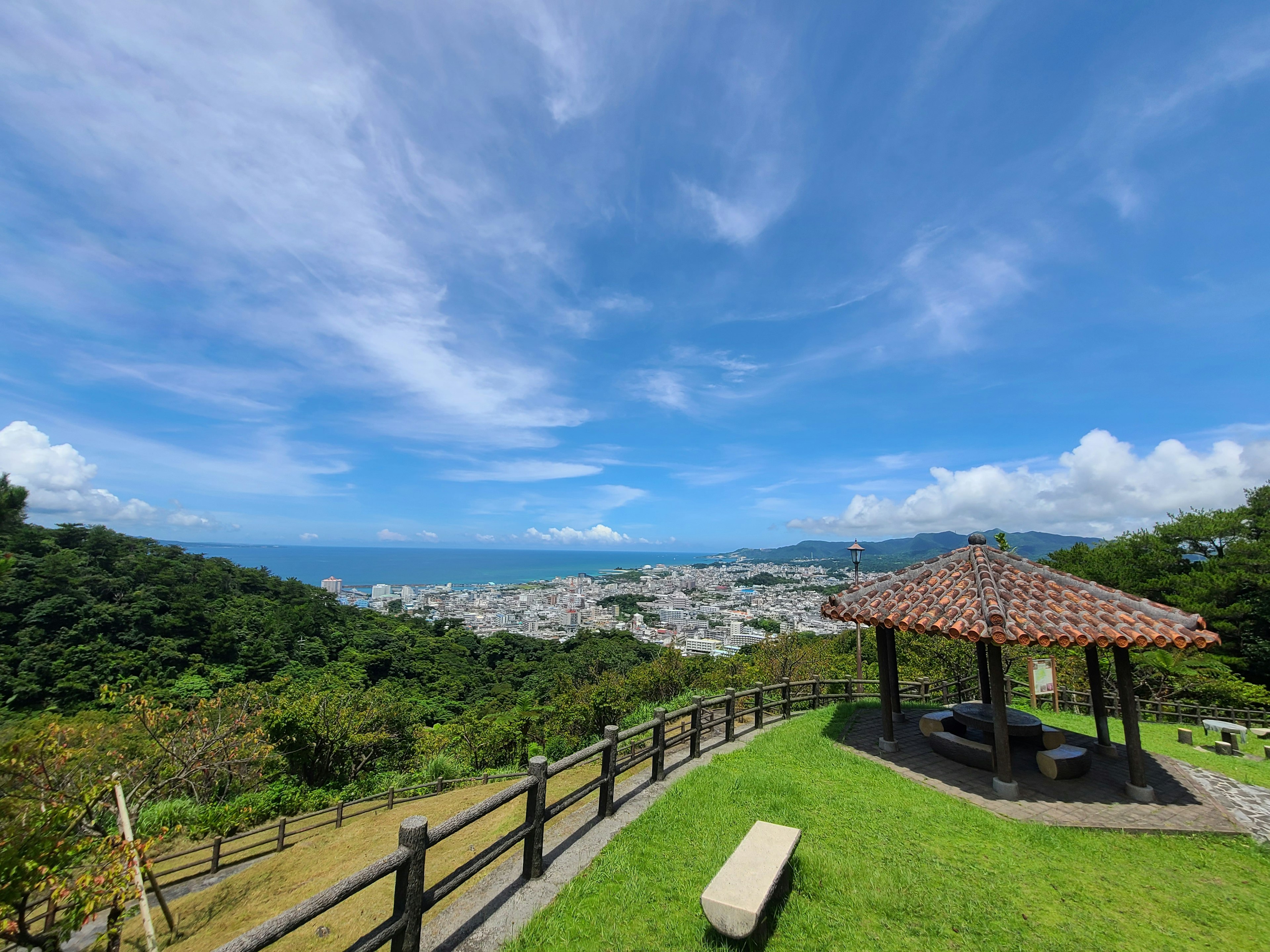 Vista escénica desde un pabellón que mira a una ladera verde vibrante y un cielo azul