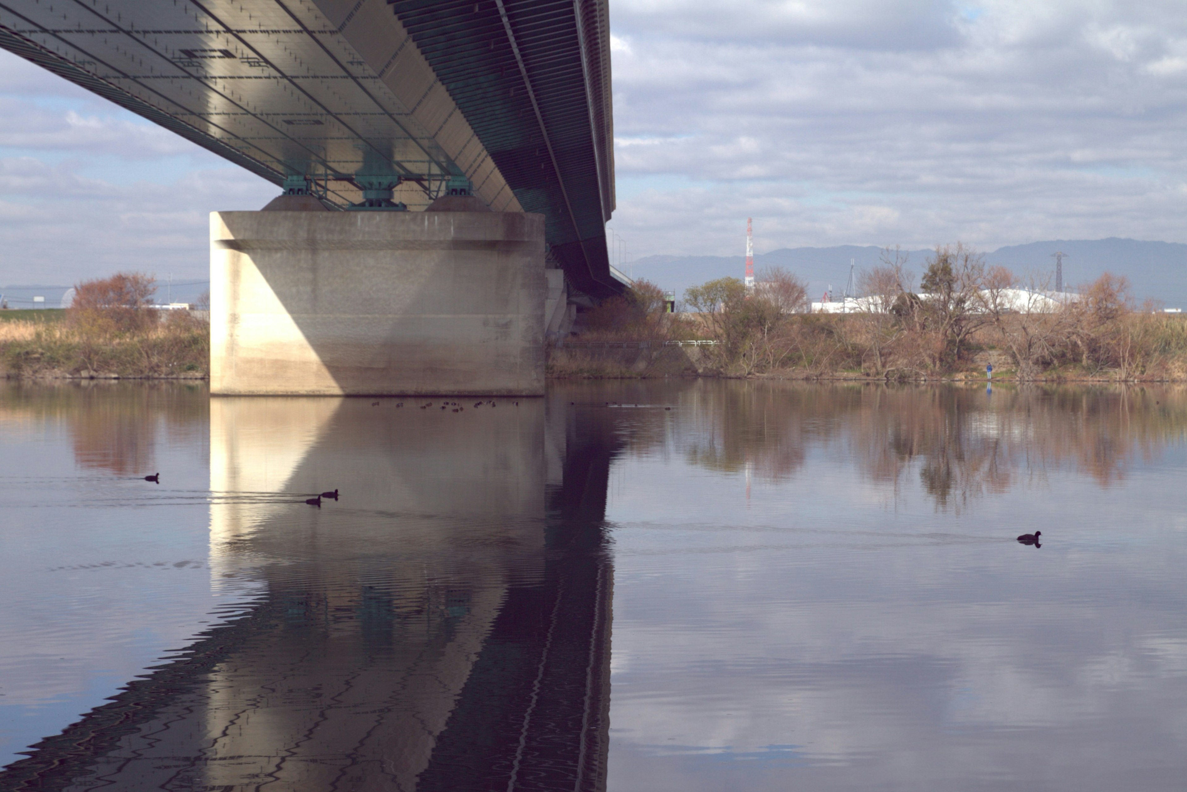 Quiet river scene under the bridge with reflections on the water