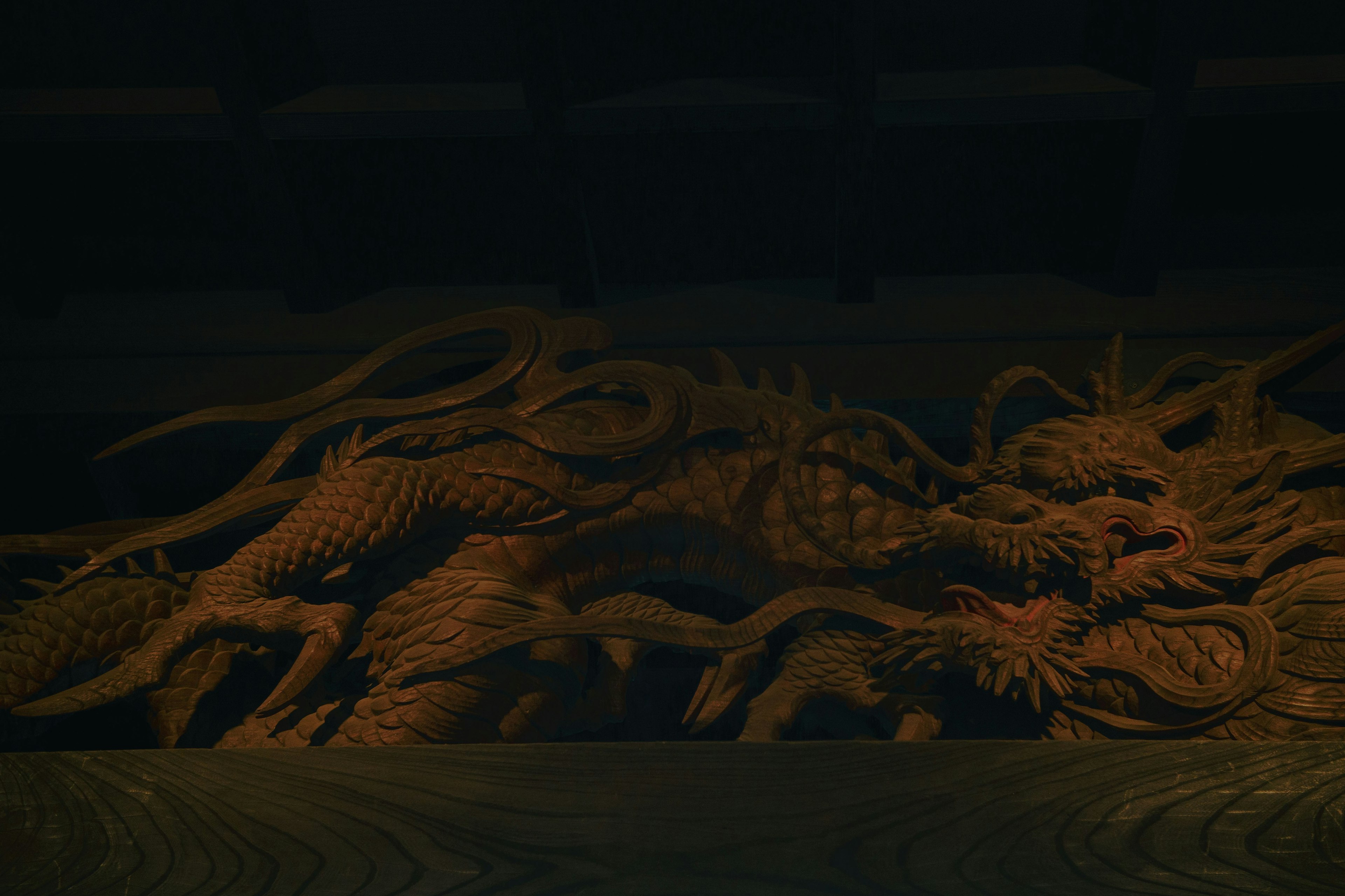 Intricate wooden dragon sculpture illuminated against a dark background