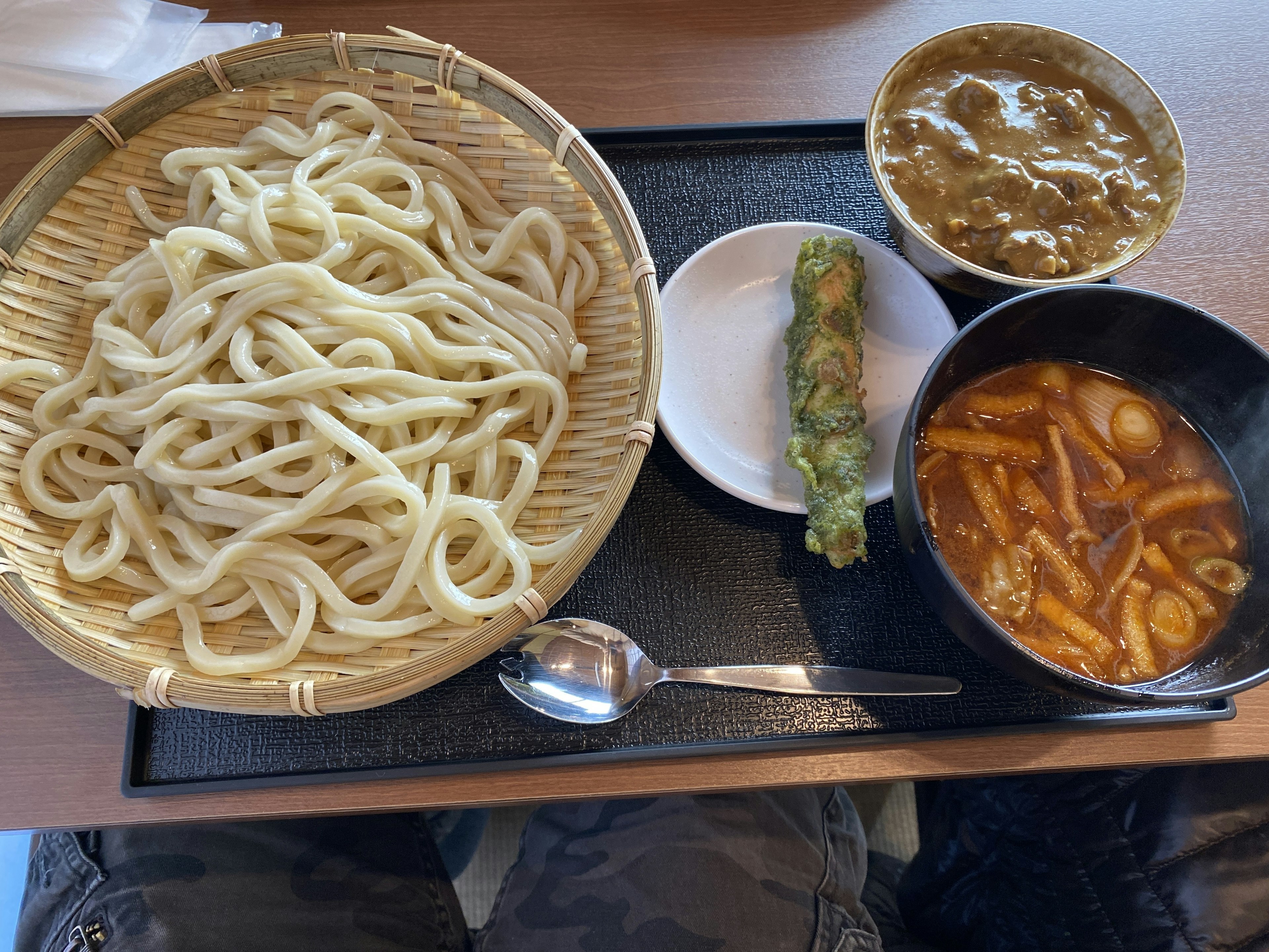 A serving of udon noodles with curry and tempura on a tray