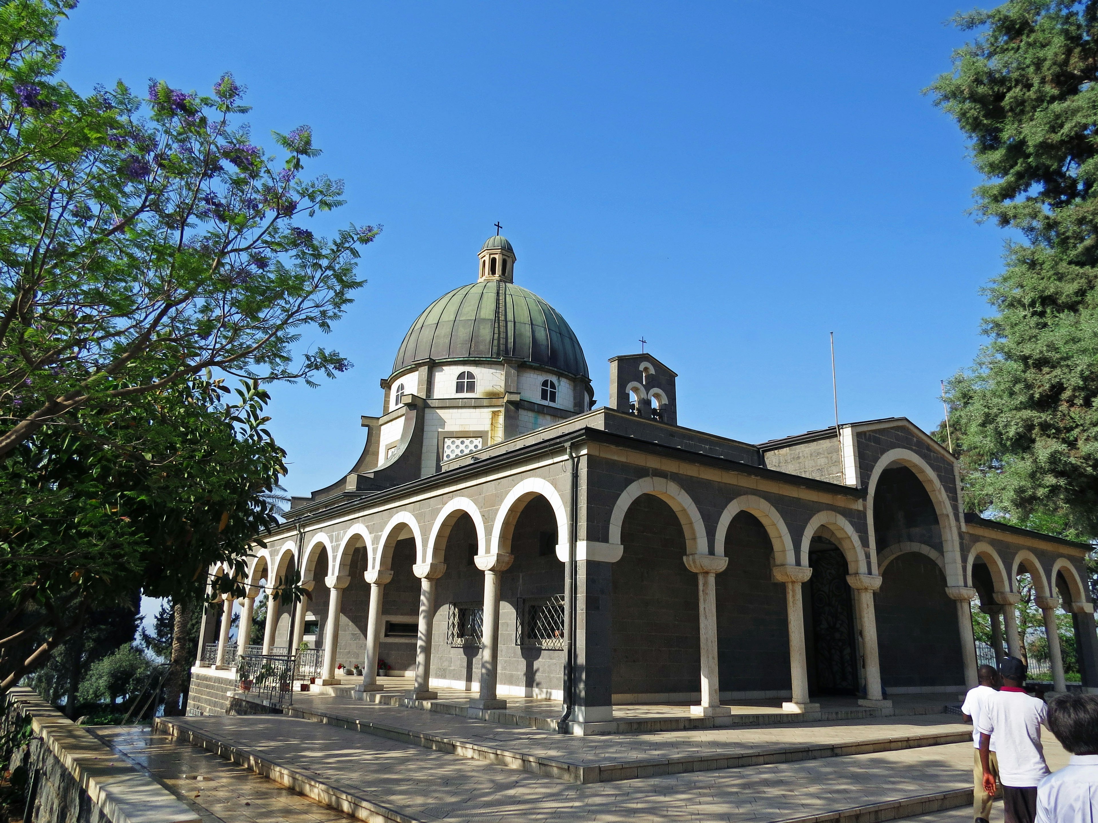 Vista esterna di un edificio con una bella cupola circondato da alberi verdi e cielo blu