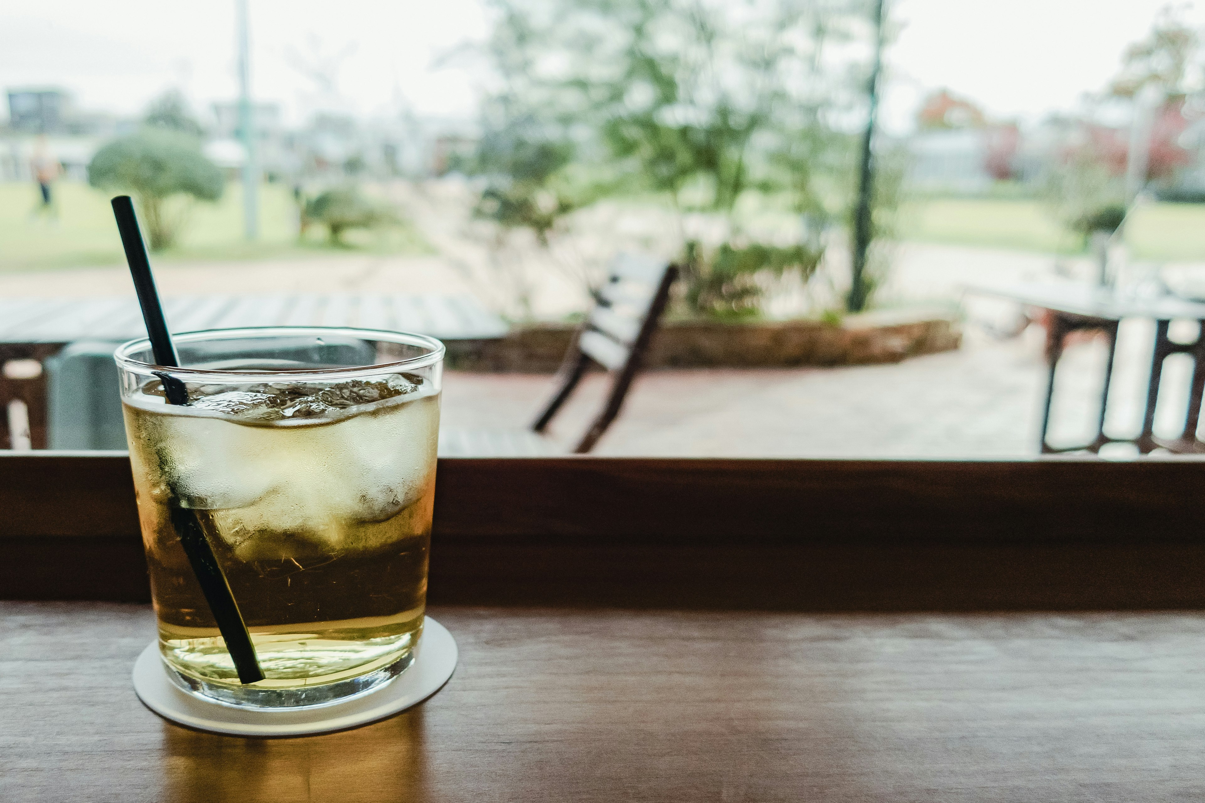 Un verre de boisson glacée sur une table en bois près de la fenêtre