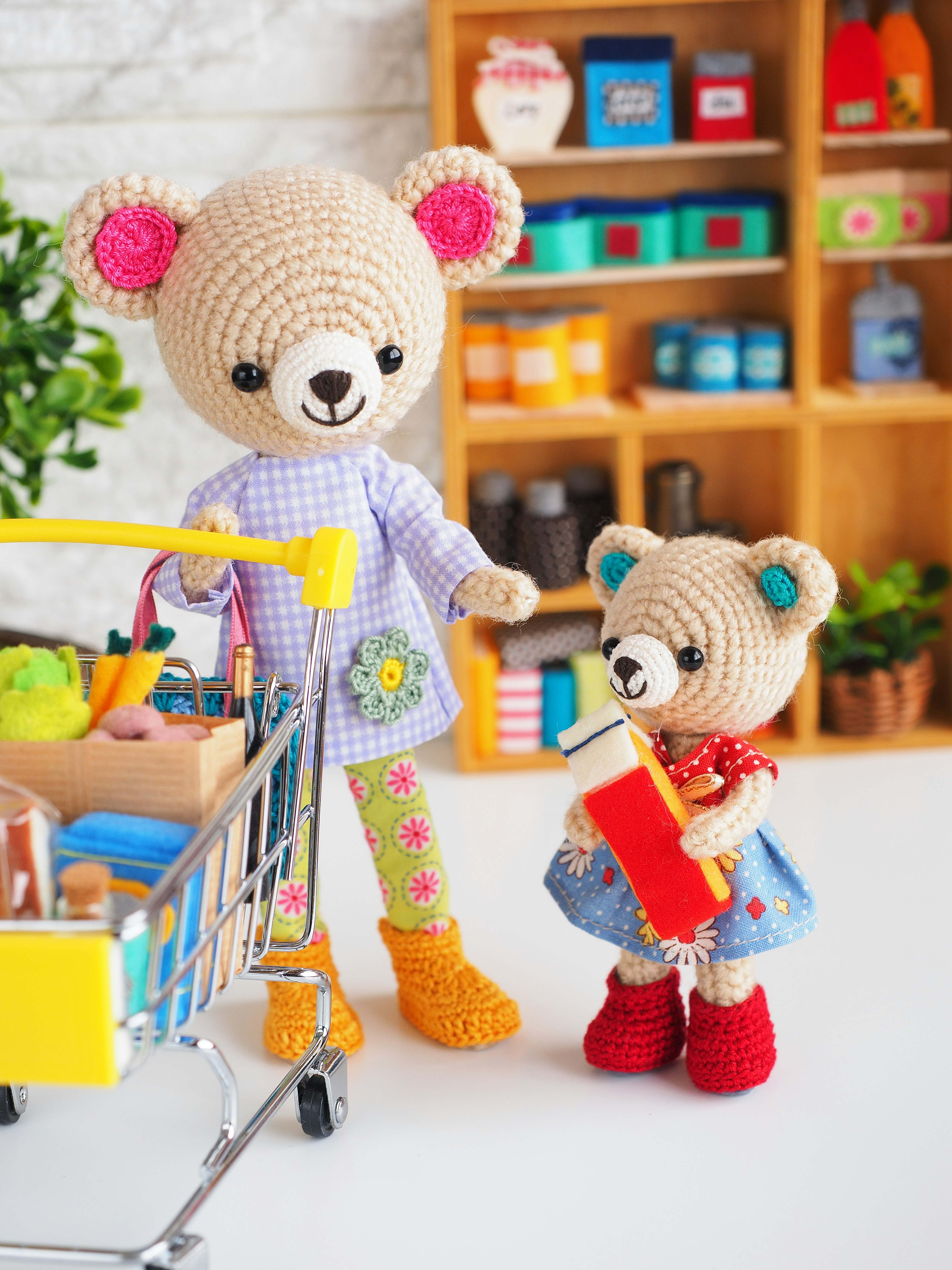 Adorable scene of crocheted bear with shopping cart and little bear holding a red book